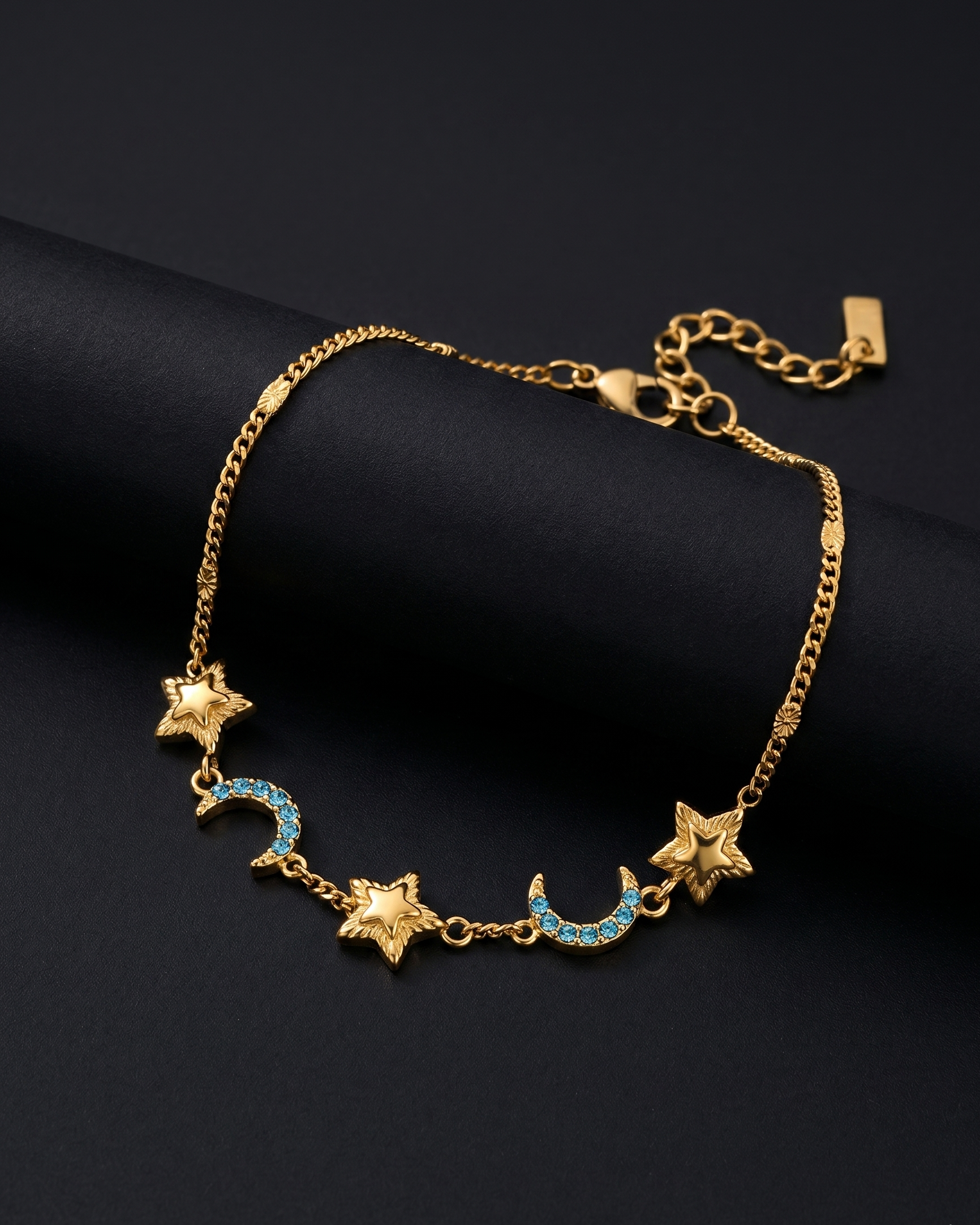 Gold bracelet with star and moon designs on a black background