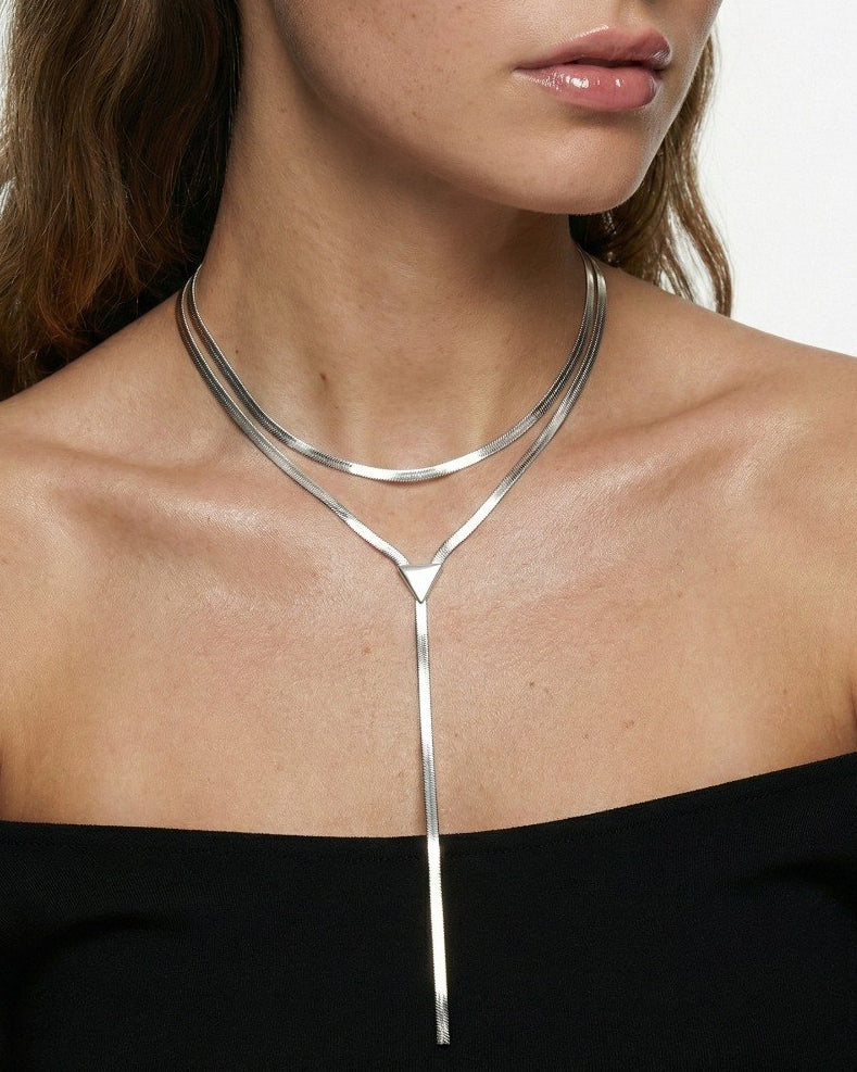 Silver necklace worn by a person against a neutral background