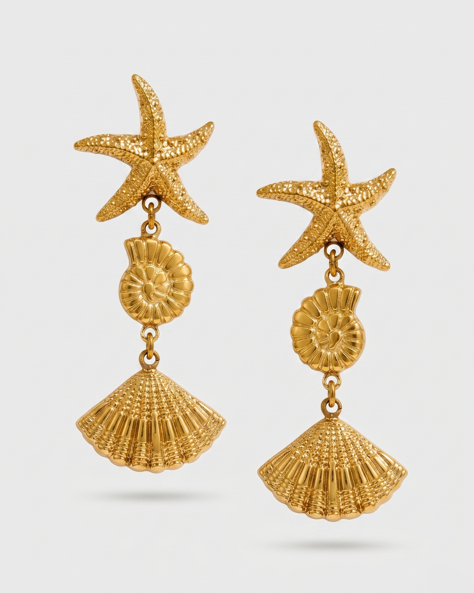 Gold starfish and shell earrings on a white background