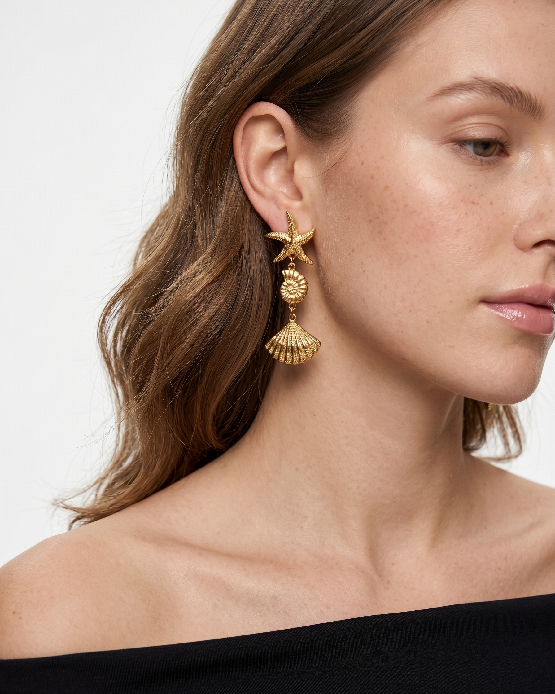 Woman wearing gold earrings with a plain background