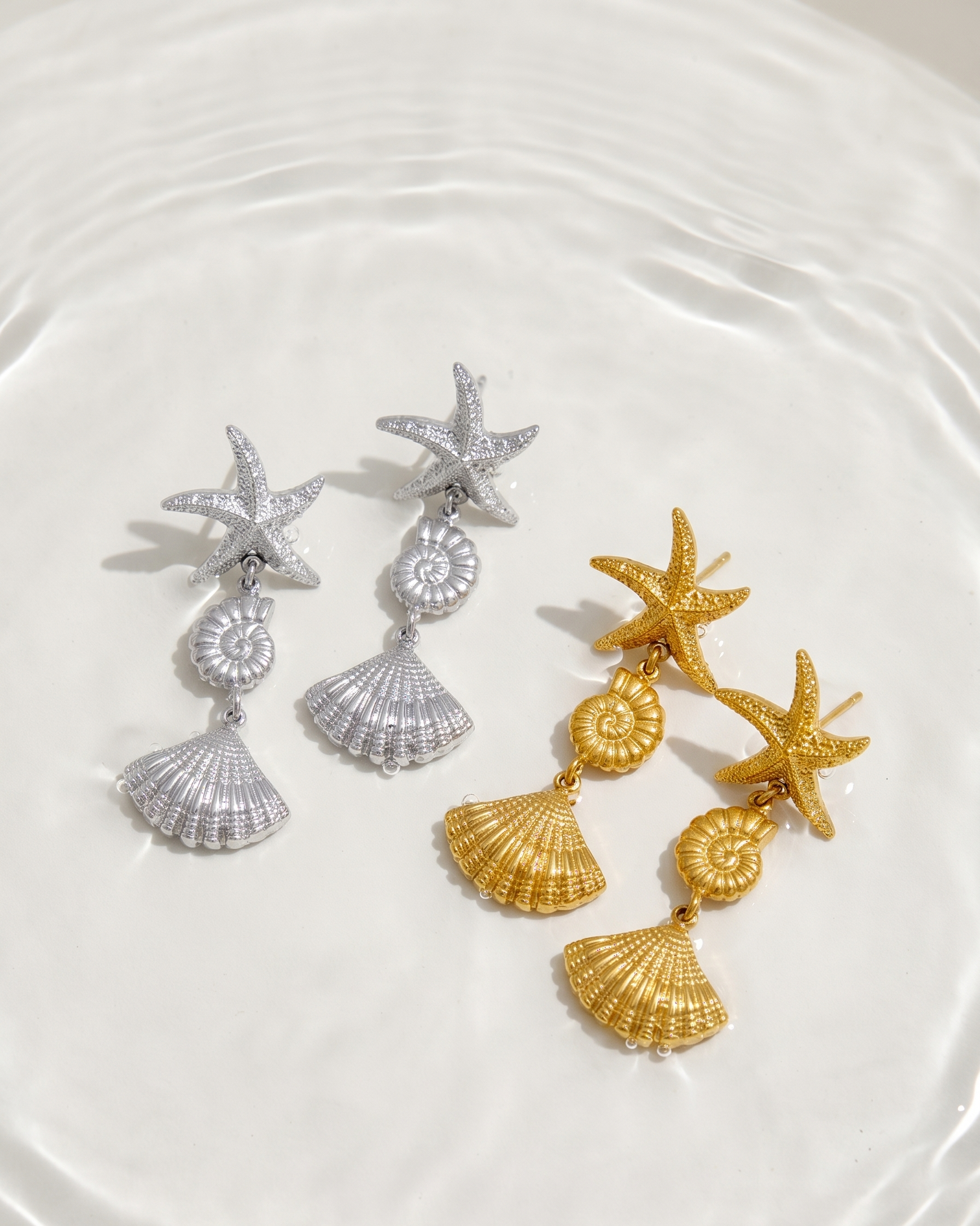 Pair of starfish and shell earrings on a white plate