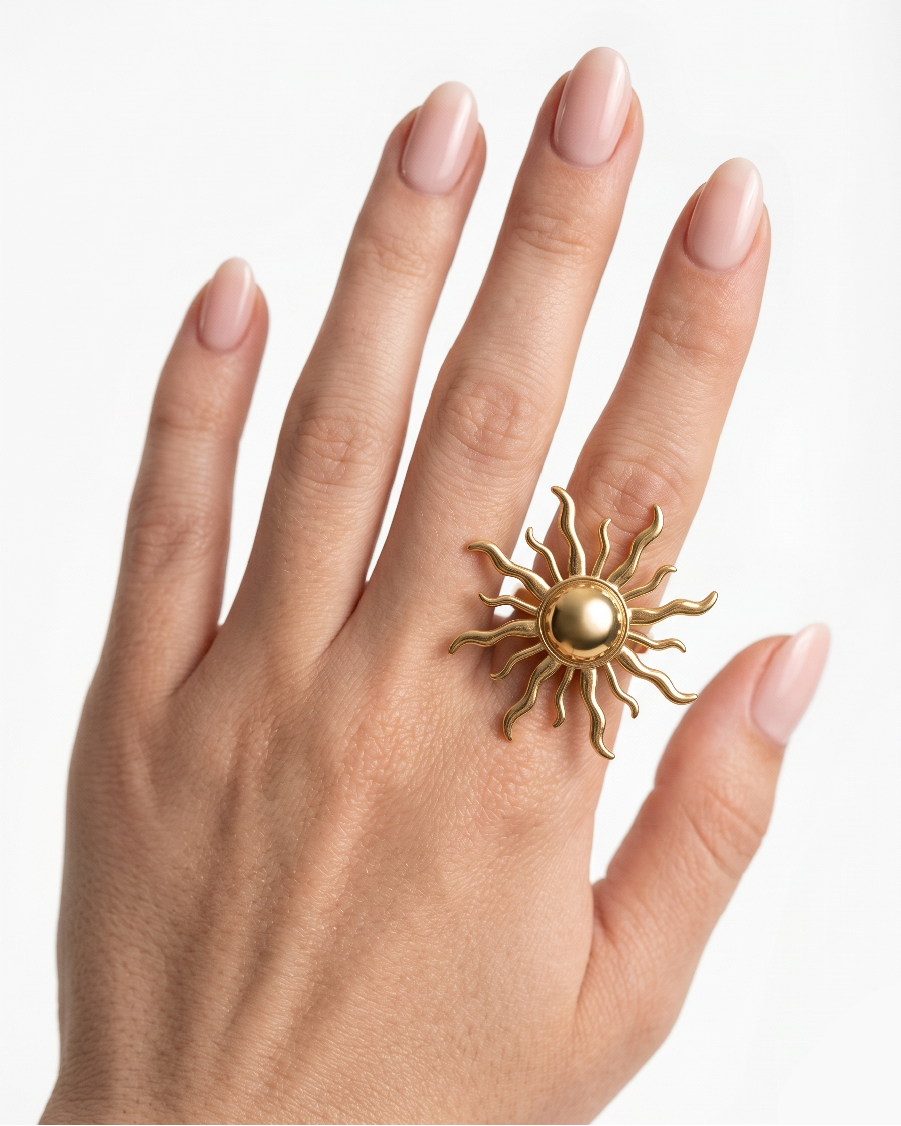 Hand wearing a gold sun-shaped ring on a white background