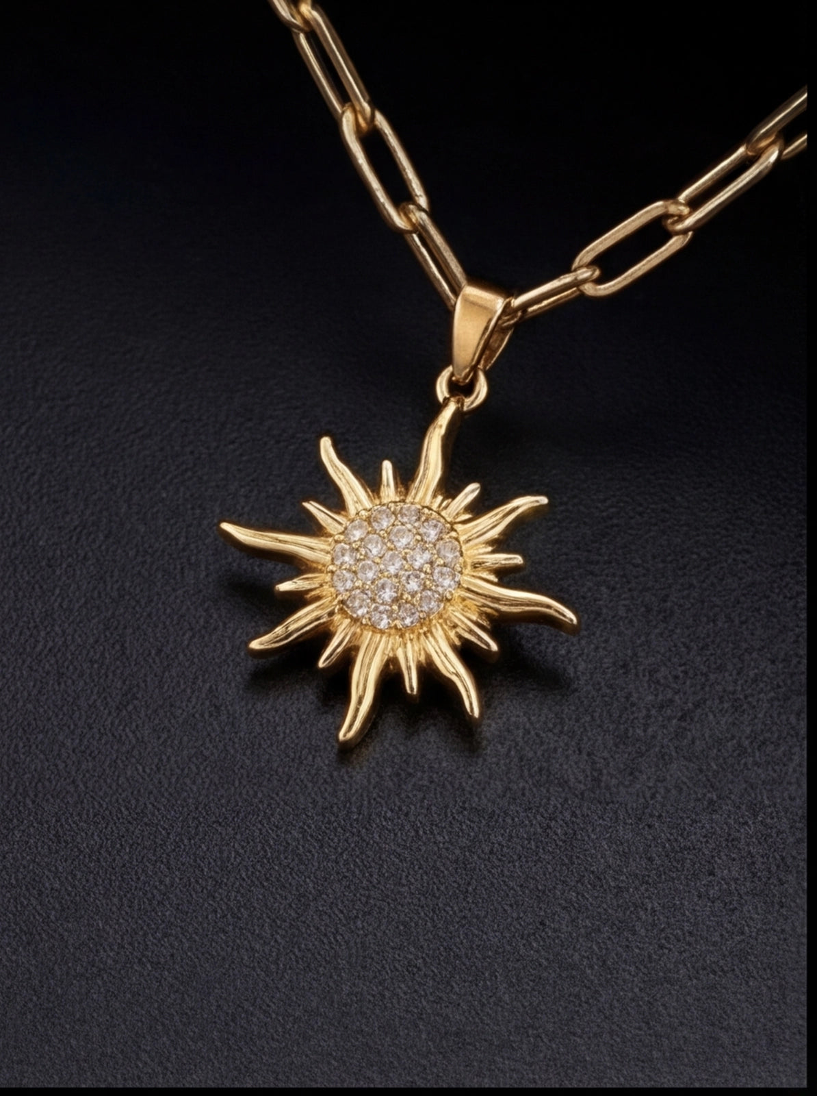 Gold sun-shaped pendant necklace on a black background