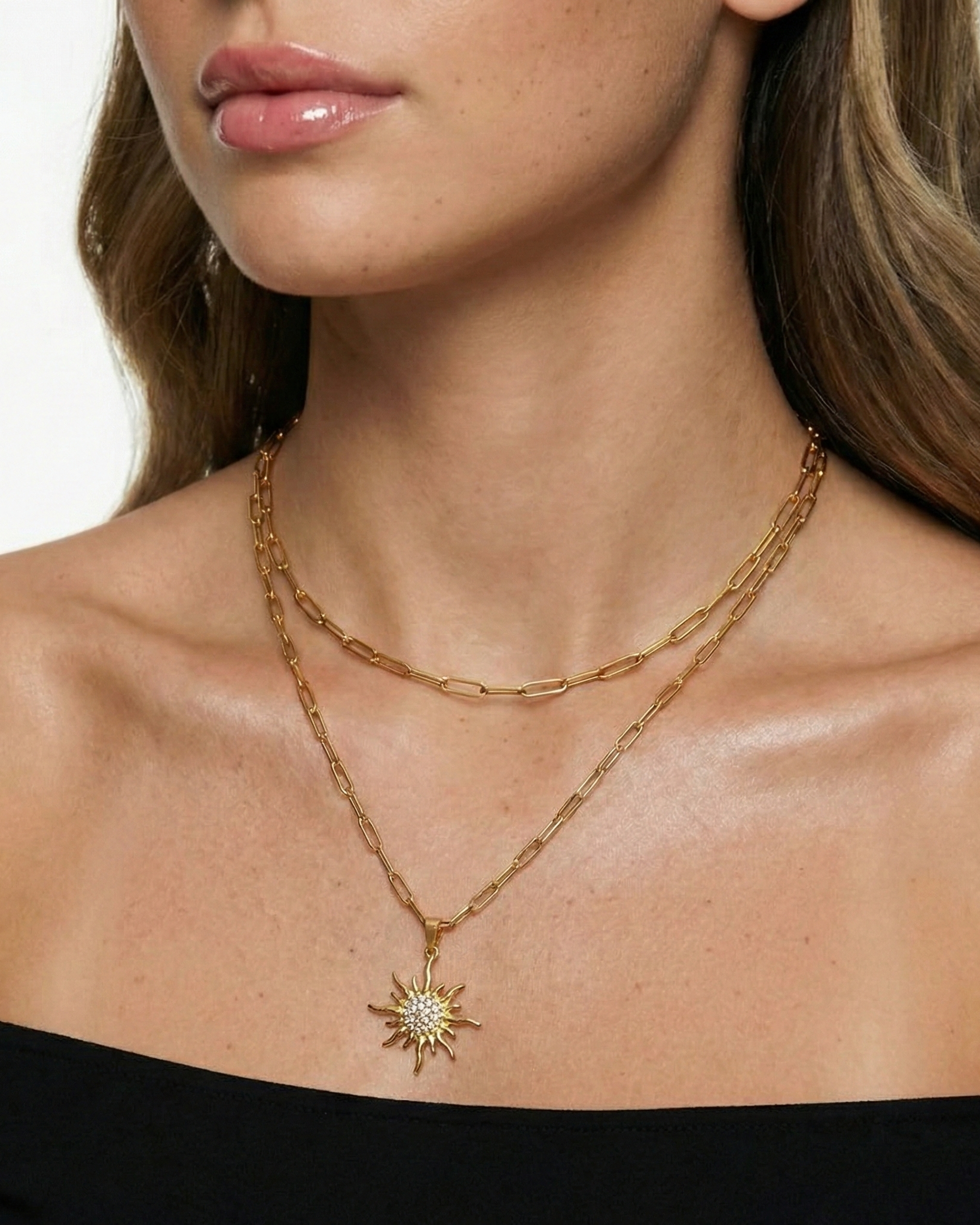 Gold necklace with a star-shaped pendant worn by a model on a white background