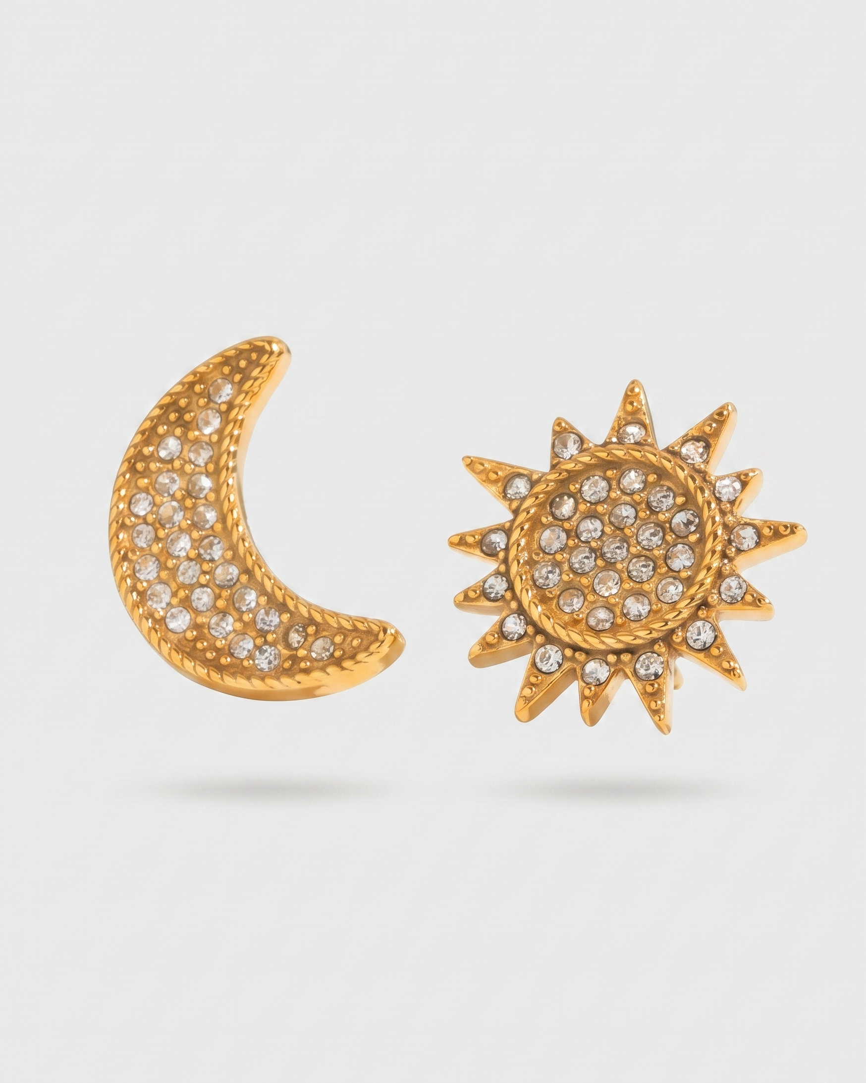 Gold moon and sun earrings with gemstones on a light gray background