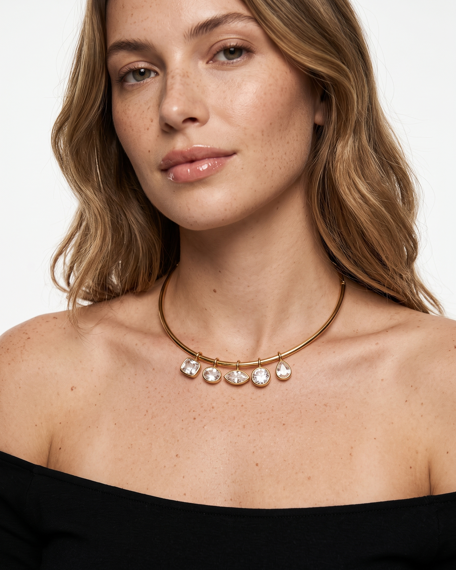 Woman wearing a gold necklace with clear stones on a white background