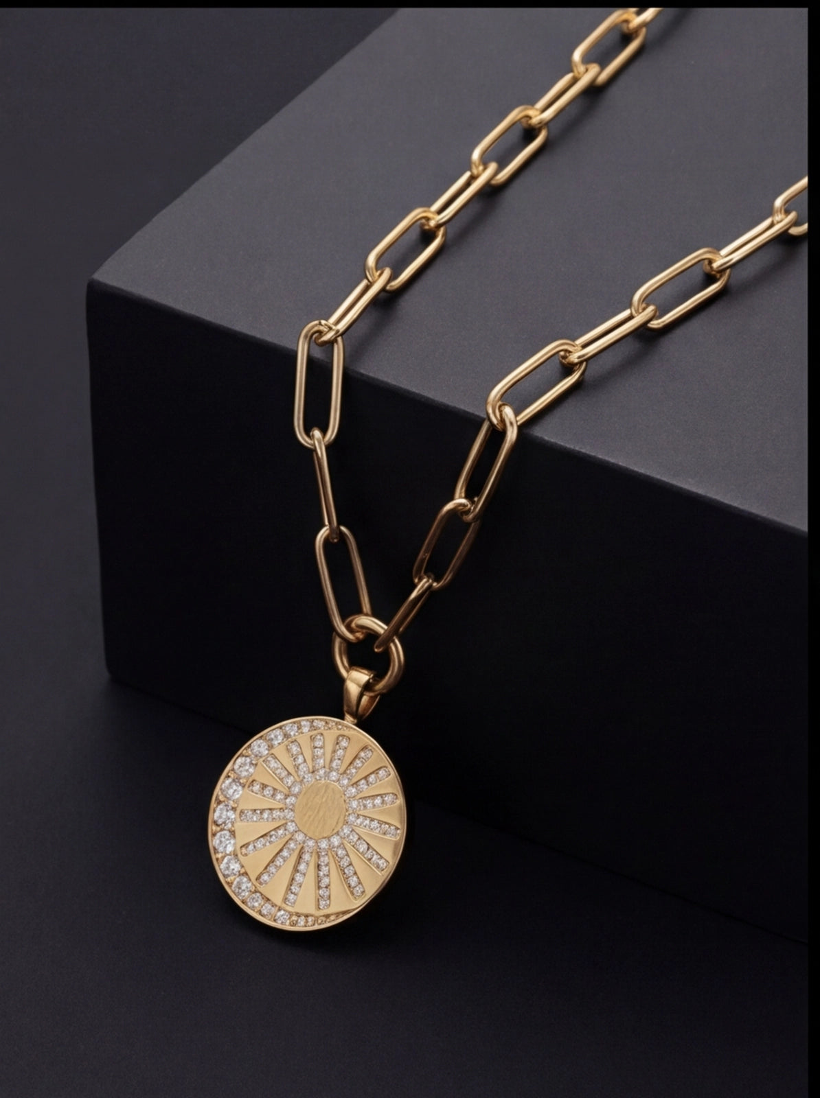 Gold chain necklace with a round pendant on a black background
