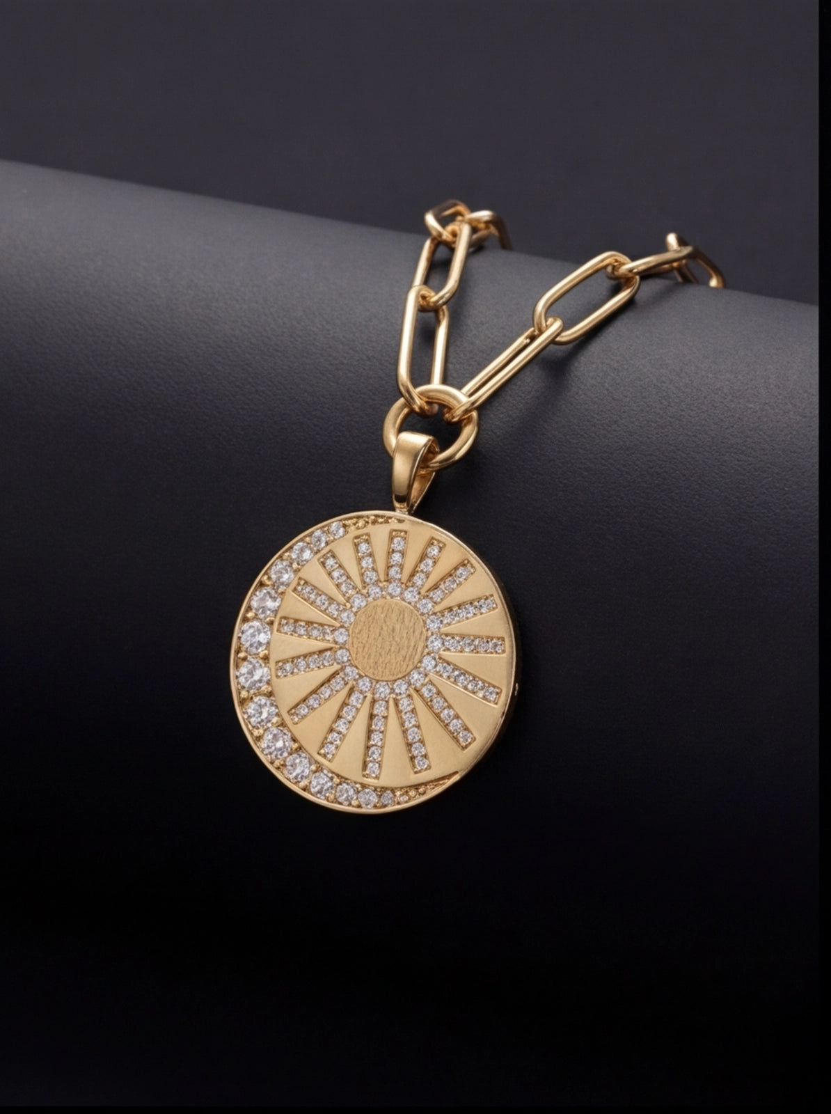 Gold necklace with a sun-shaped pendant on a dark background