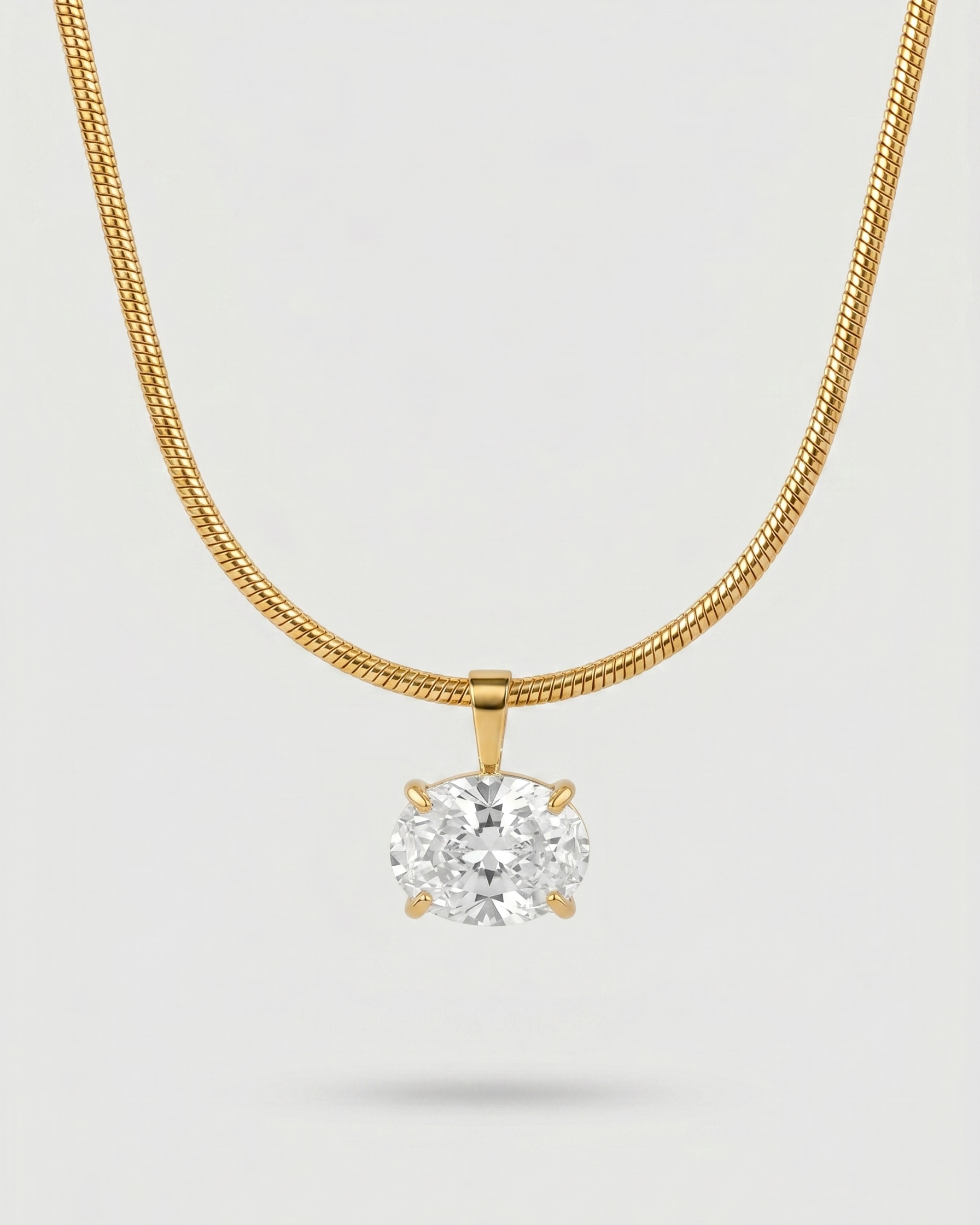 Gold necklace with a diamond pendant on a light gray background