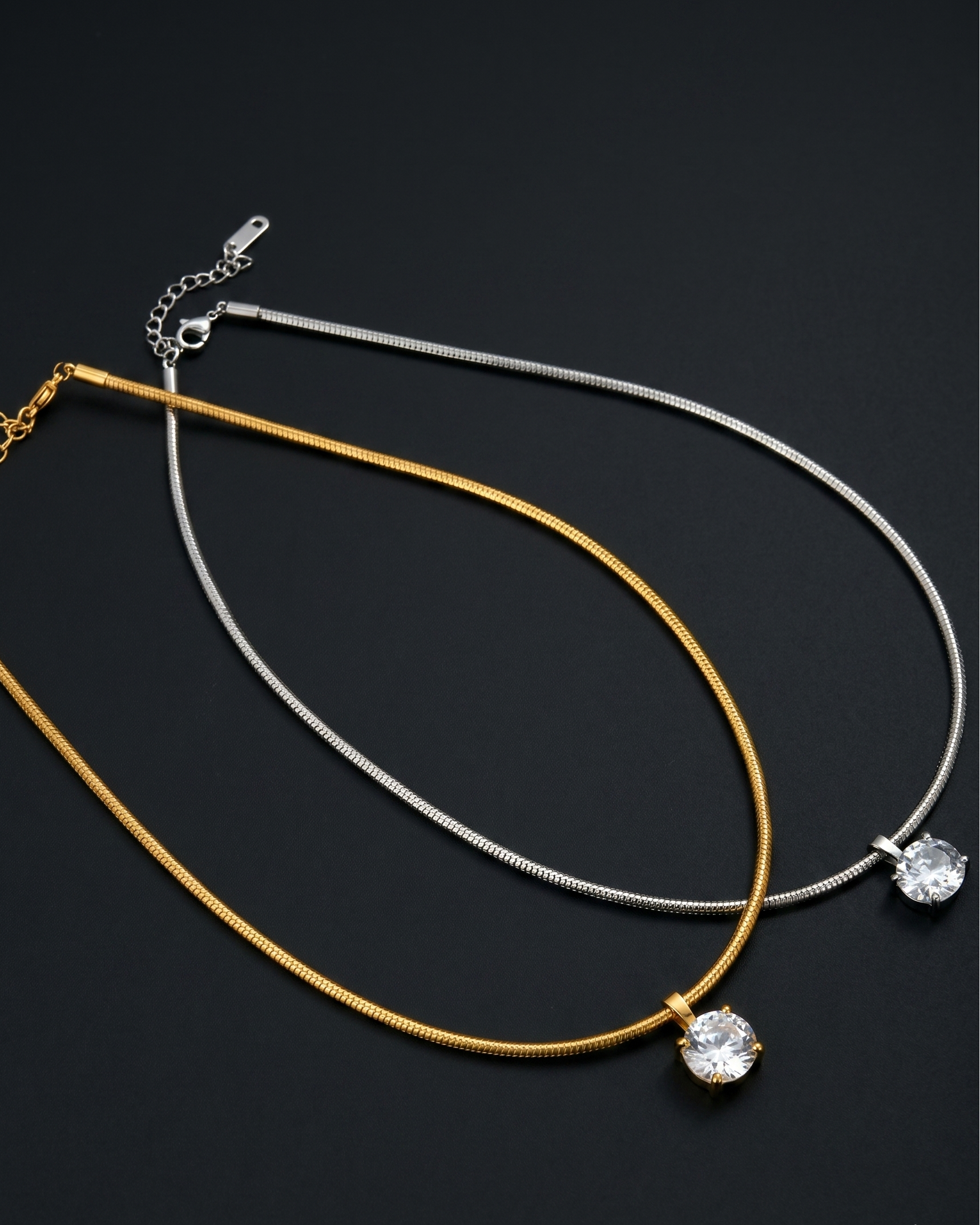Two necklaces, one gold and one silver, on a black background.
