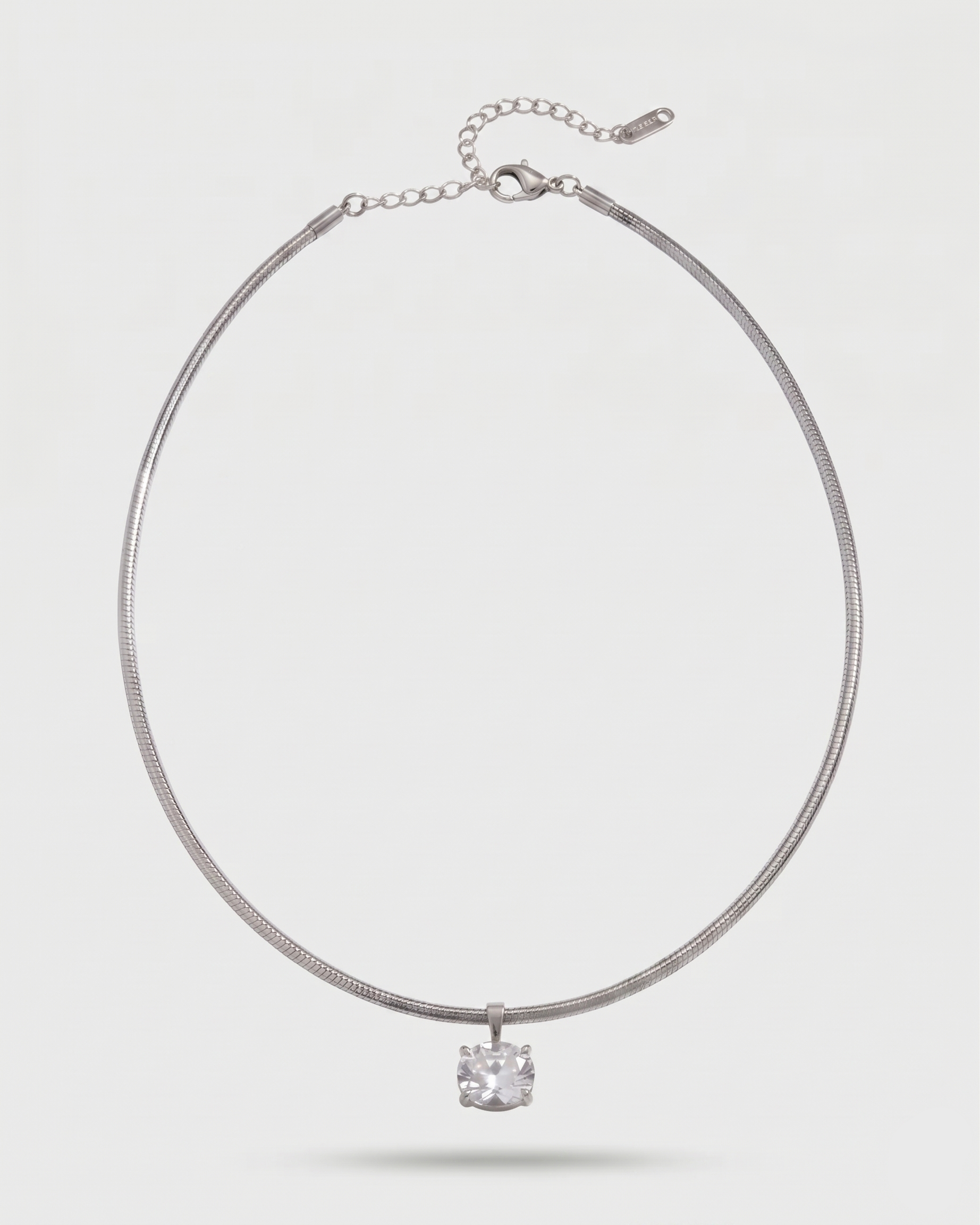Silver necklace with a small pendant on a light gray background