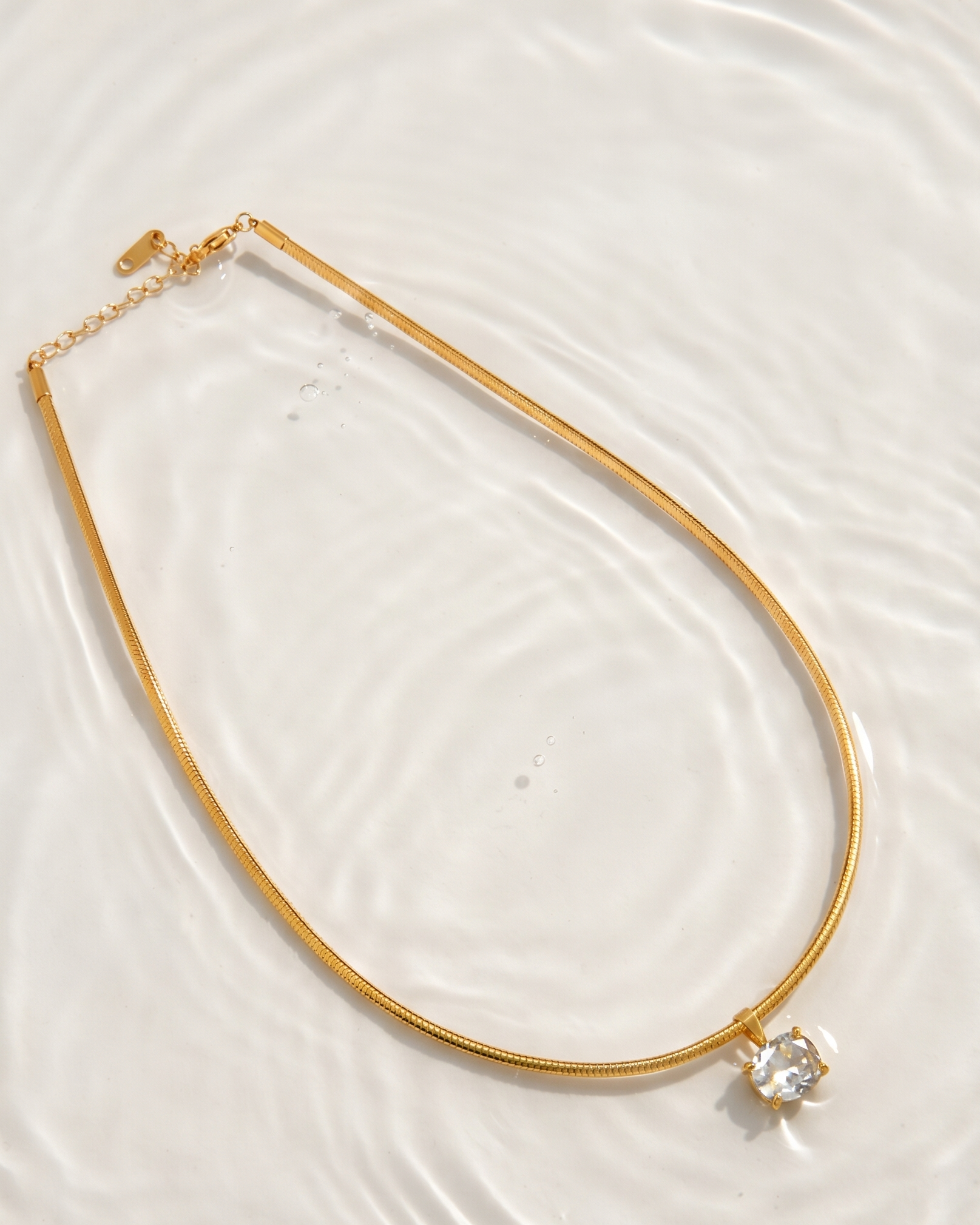 Gold necklace with a diamond pendant on a white background
