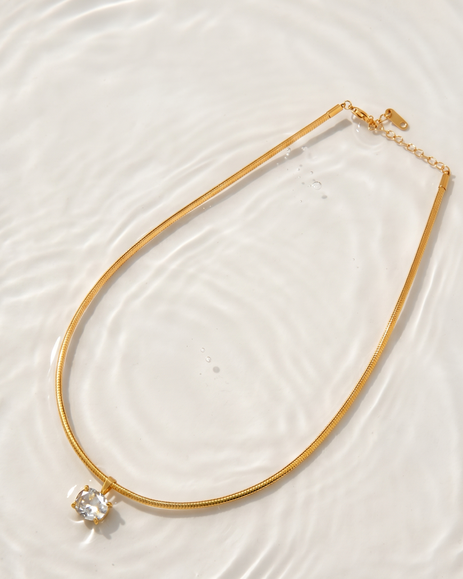 Gold necklace with a diamond pendant on a white background