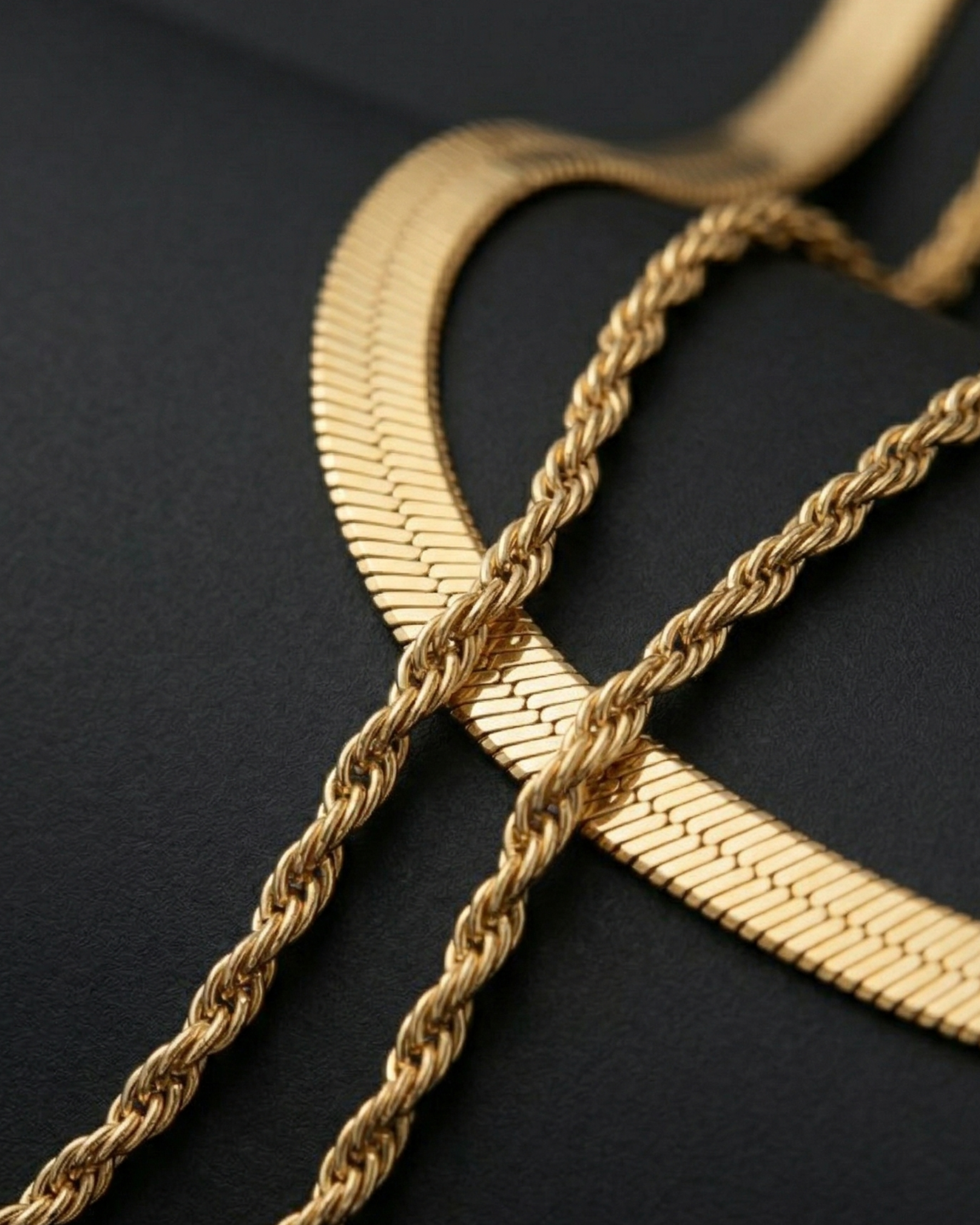 Three gold necklaces of different designs on a black background