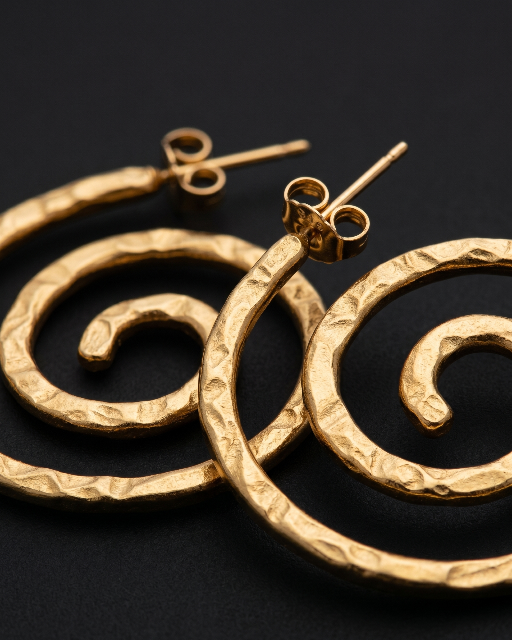 Gold spiral earrings on a black background