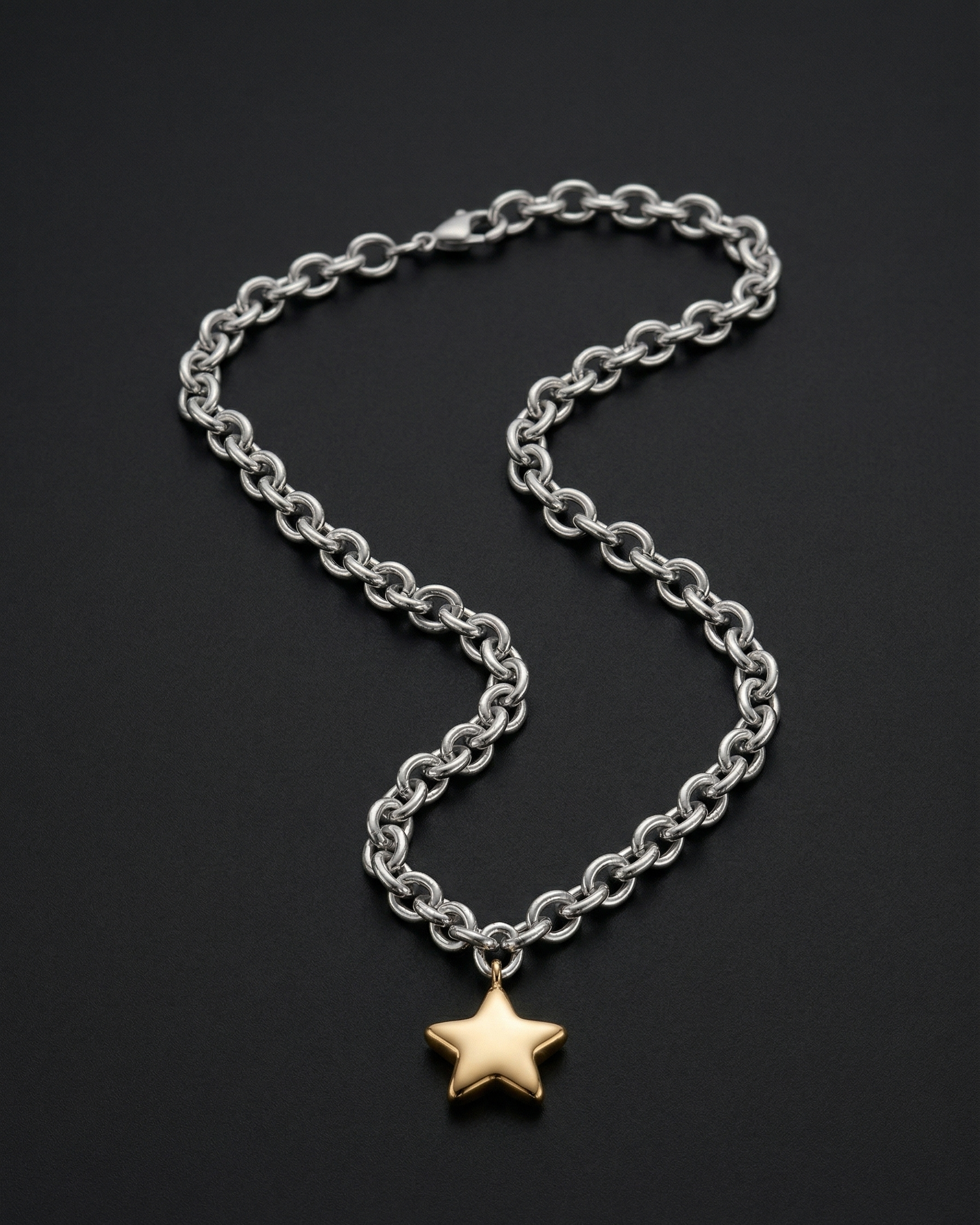 Silver chain necklace with a gold star pendant on a black background