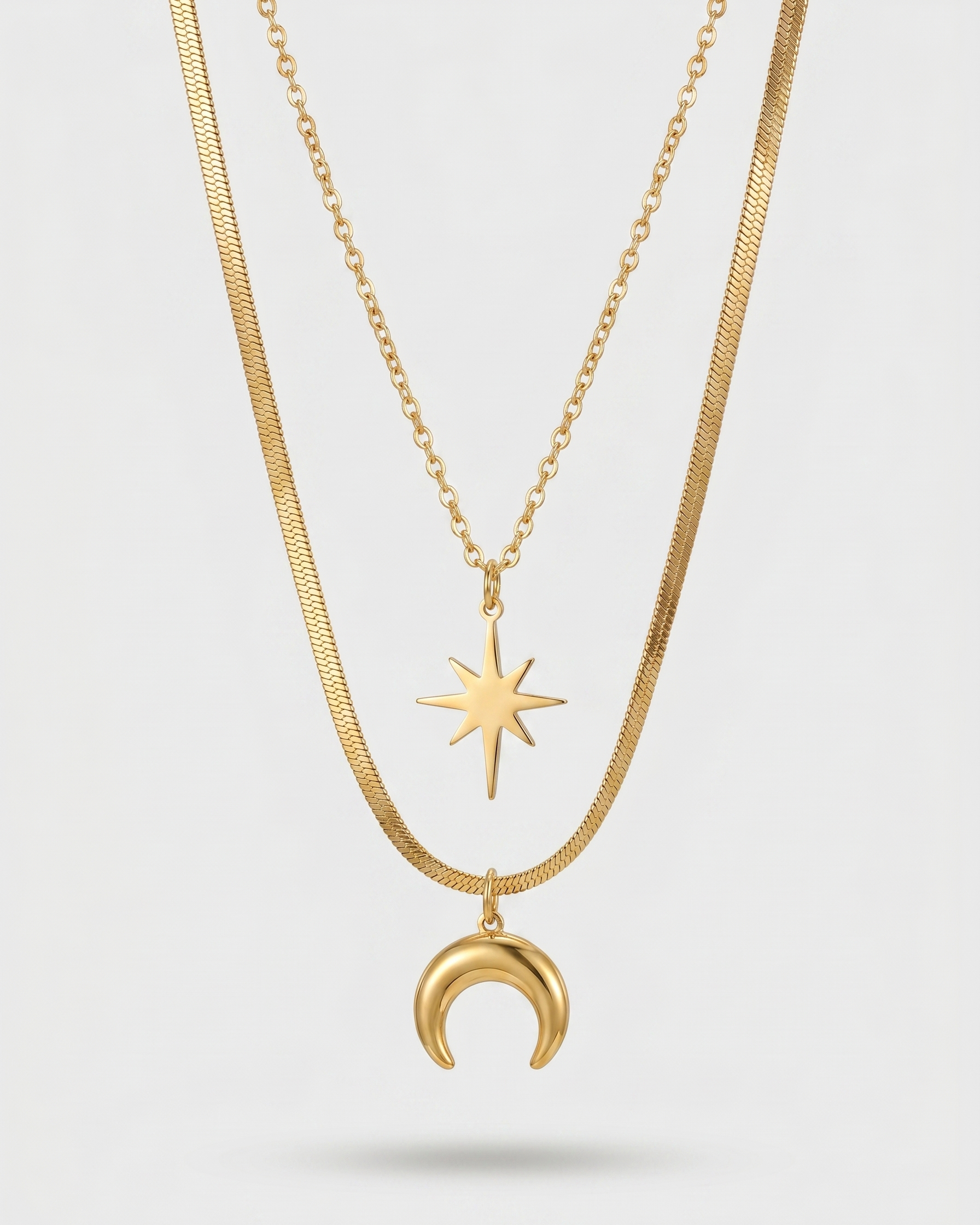Two gold necklaces with star and moon pendants on a light gray background