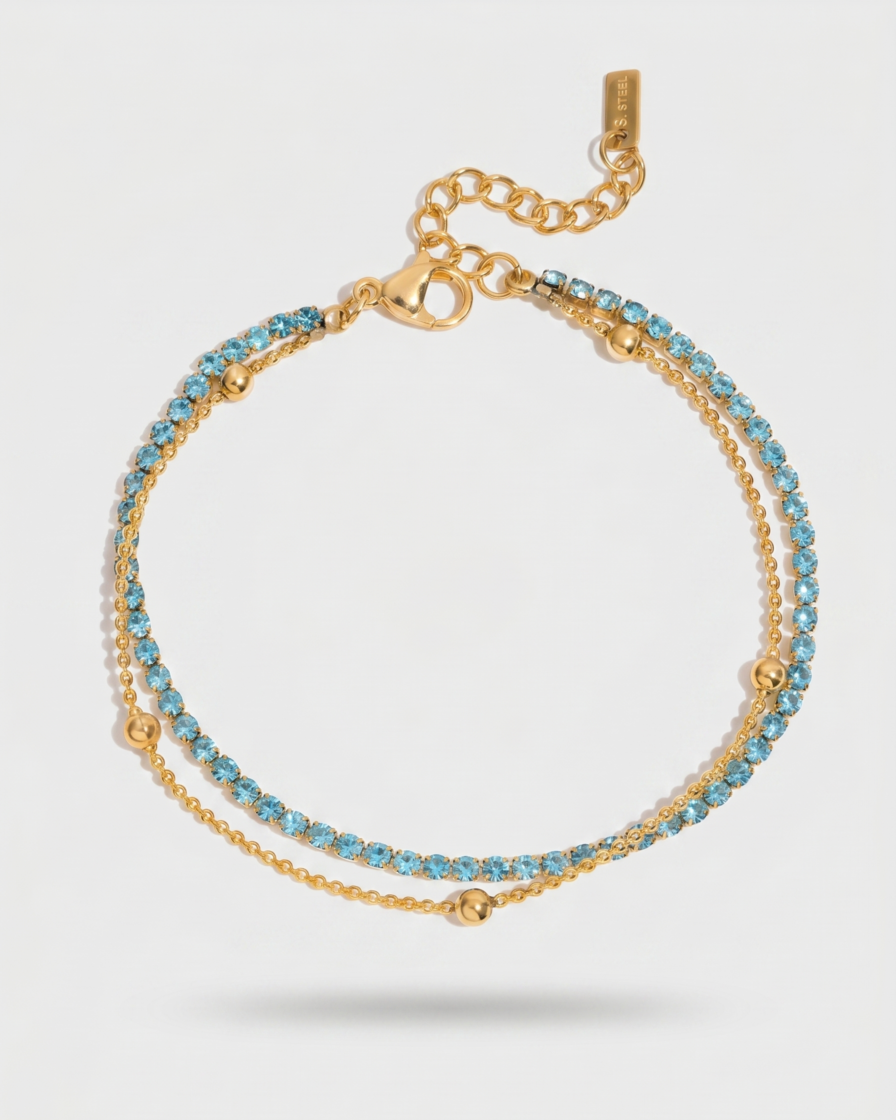 Gold bracelet with blue stones on a light gray background