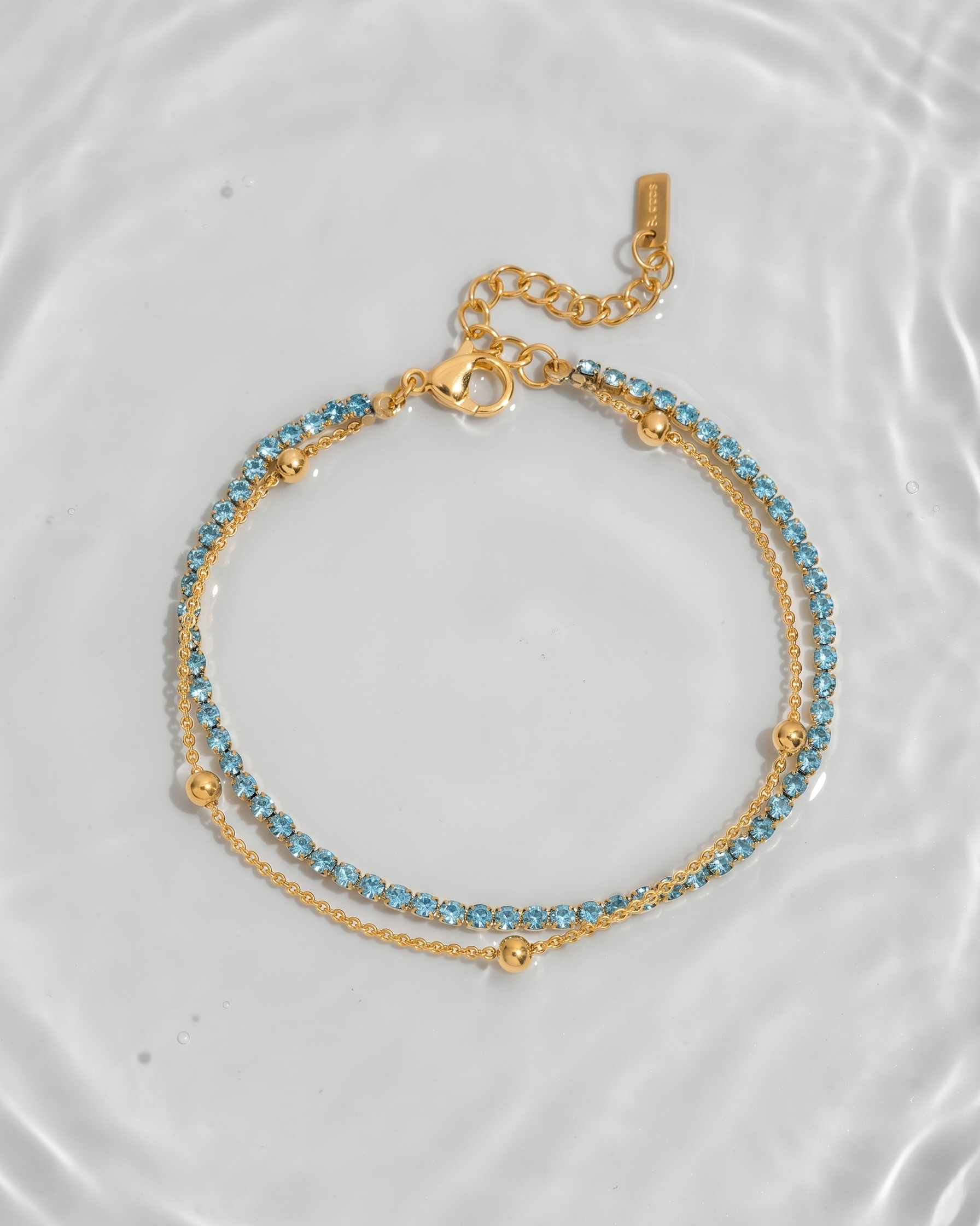 Gold bracelet with blue beads on a white plate