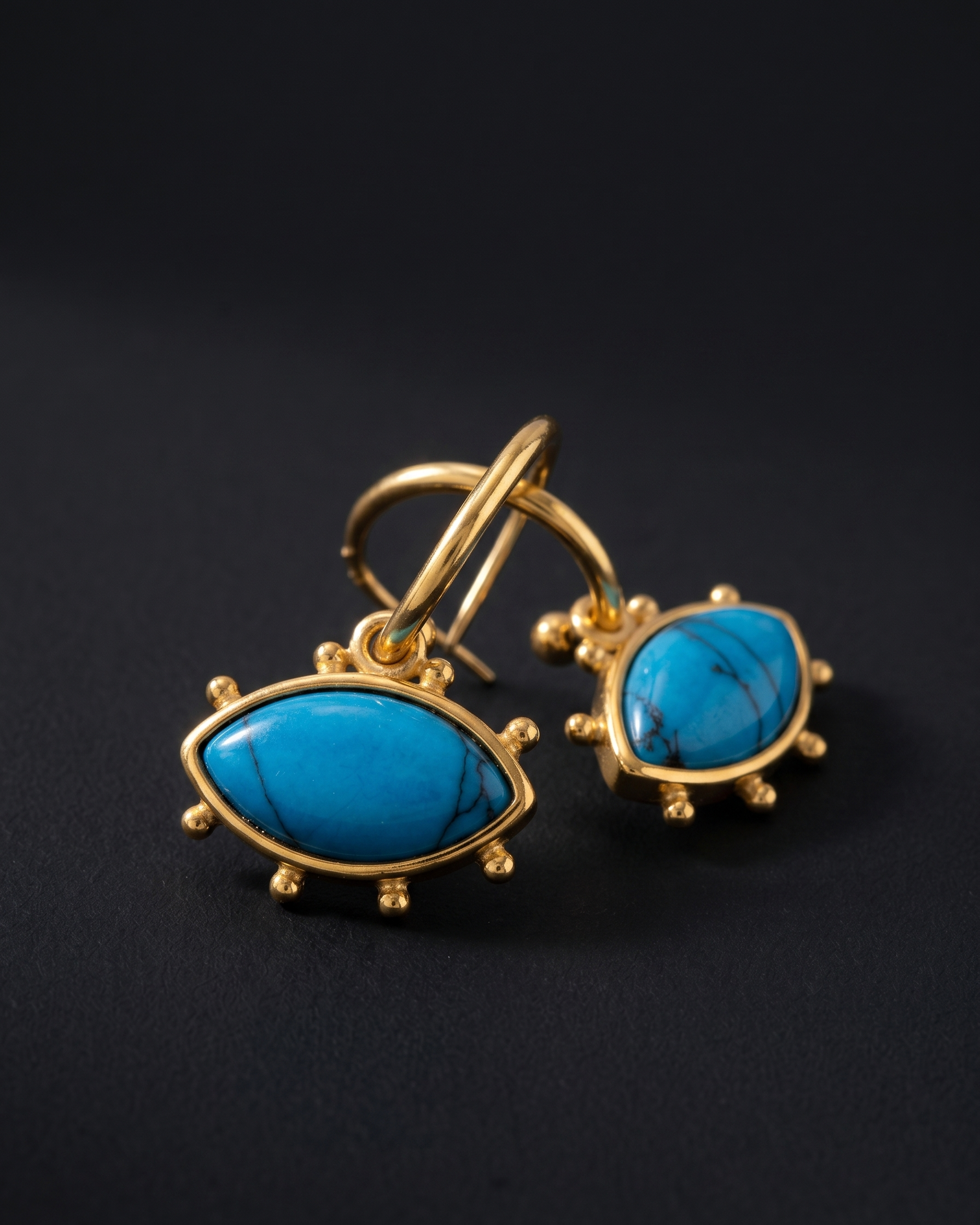 Gold earrings with turquoise stones on a black background