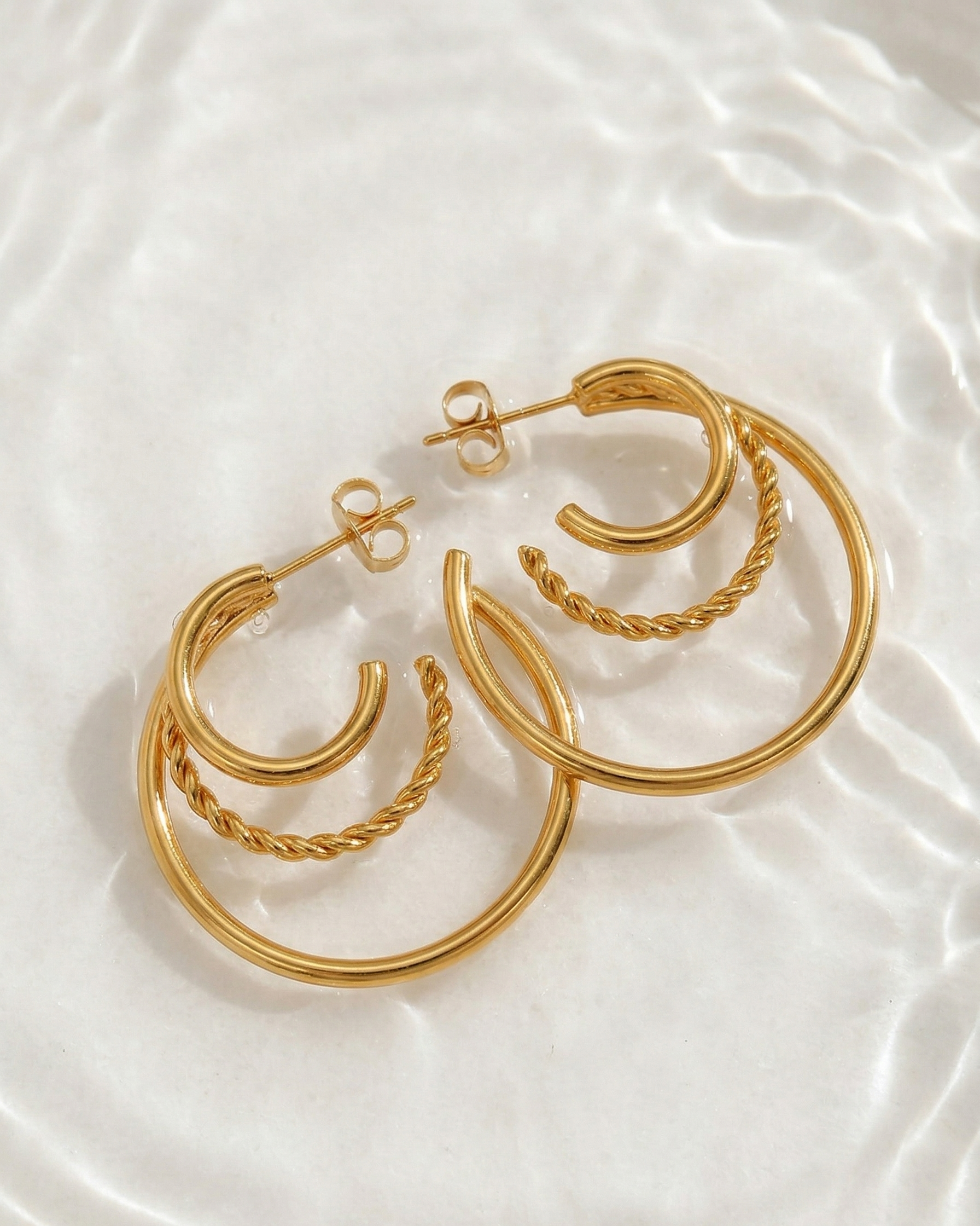 Set of gold hoop earrings on a white fabric background