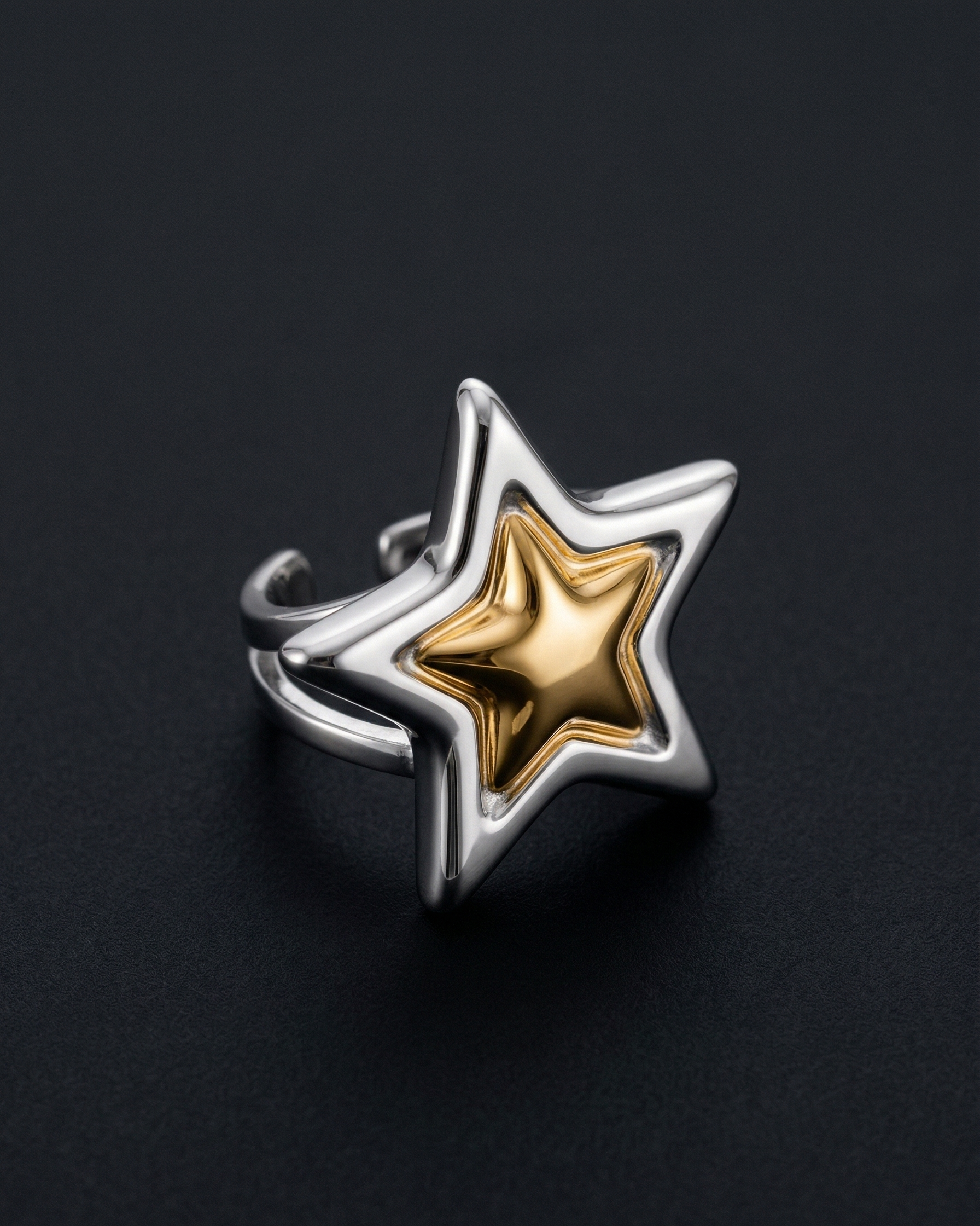 Star-shaped ring with gold center and silver outline on a black background