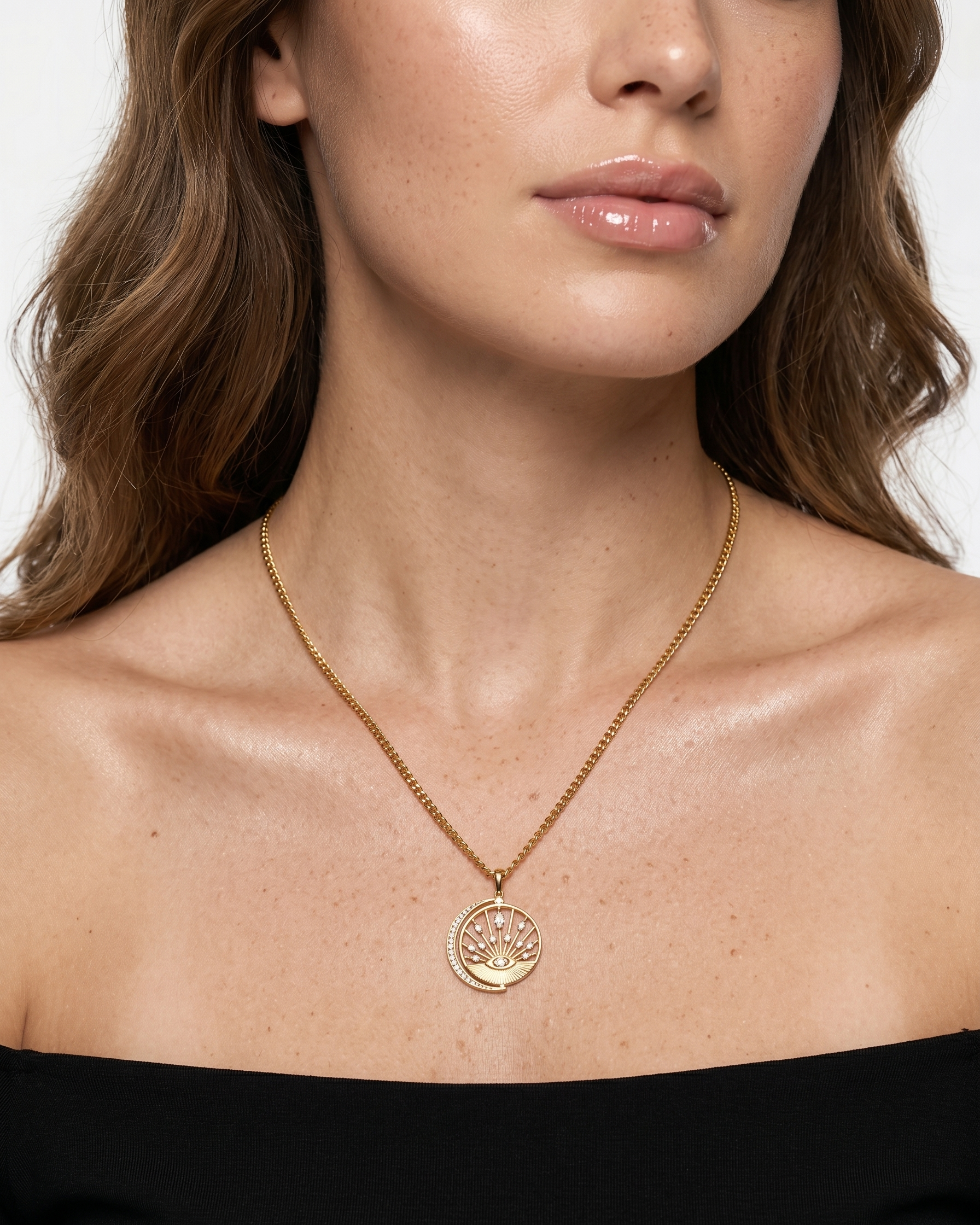 Close-up of a woman wearing a gold necklace with a pendant on a plain background
