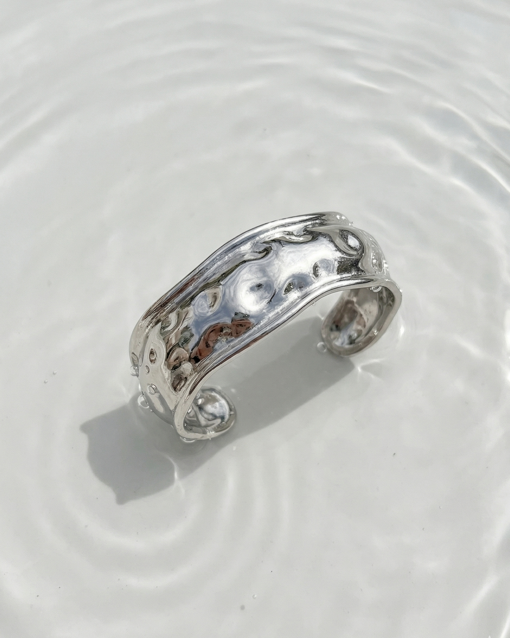 Silver ring on a white surface with water ripples