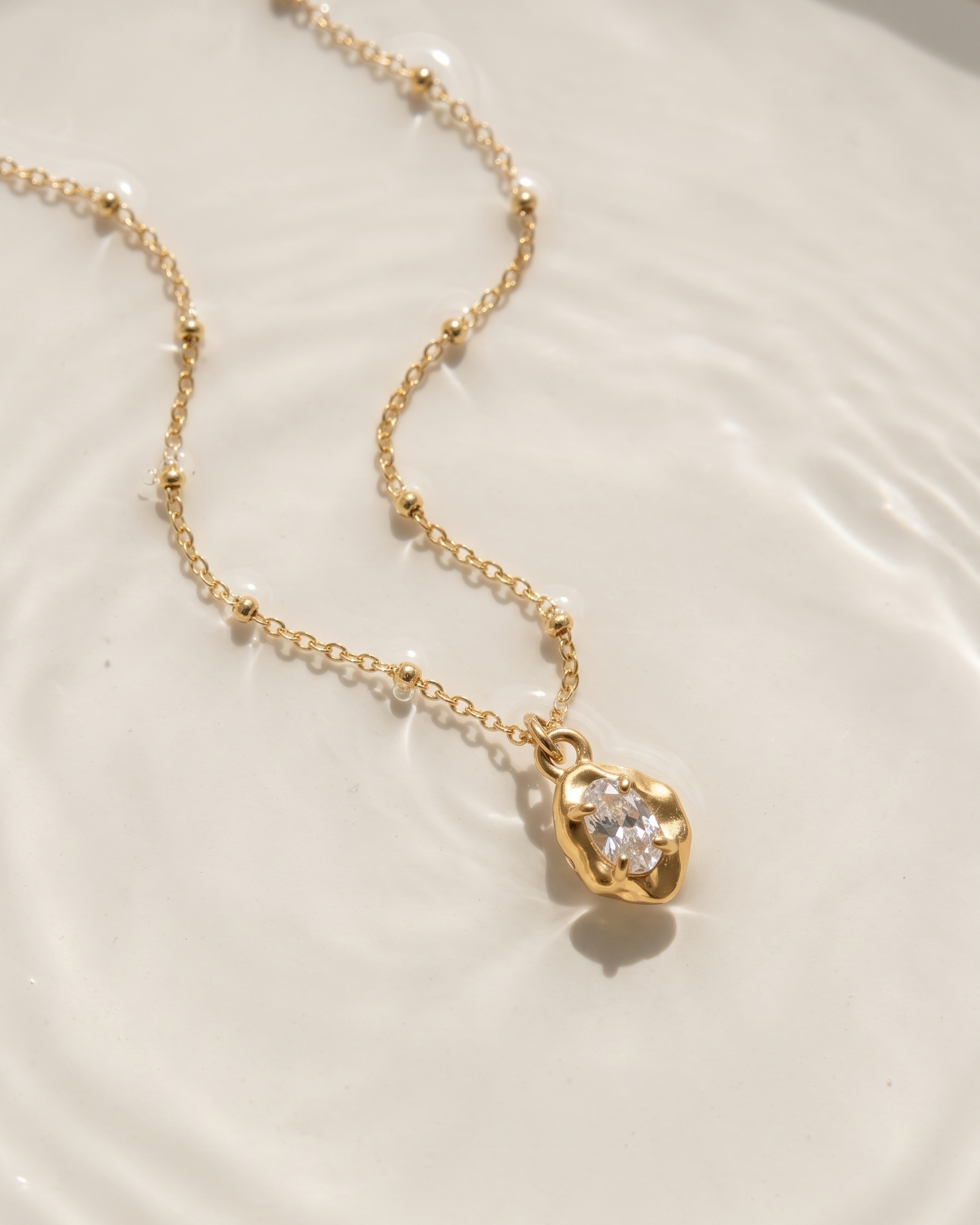 Gold necklace with a pendant on a white plate