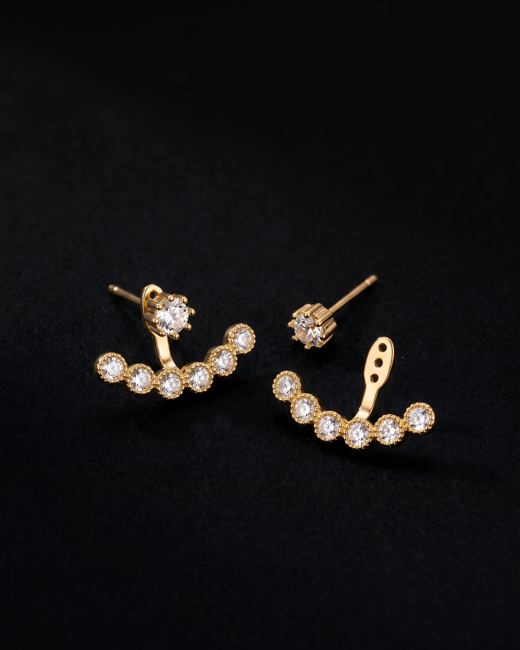Gold earrings with clear gemstones on a black background