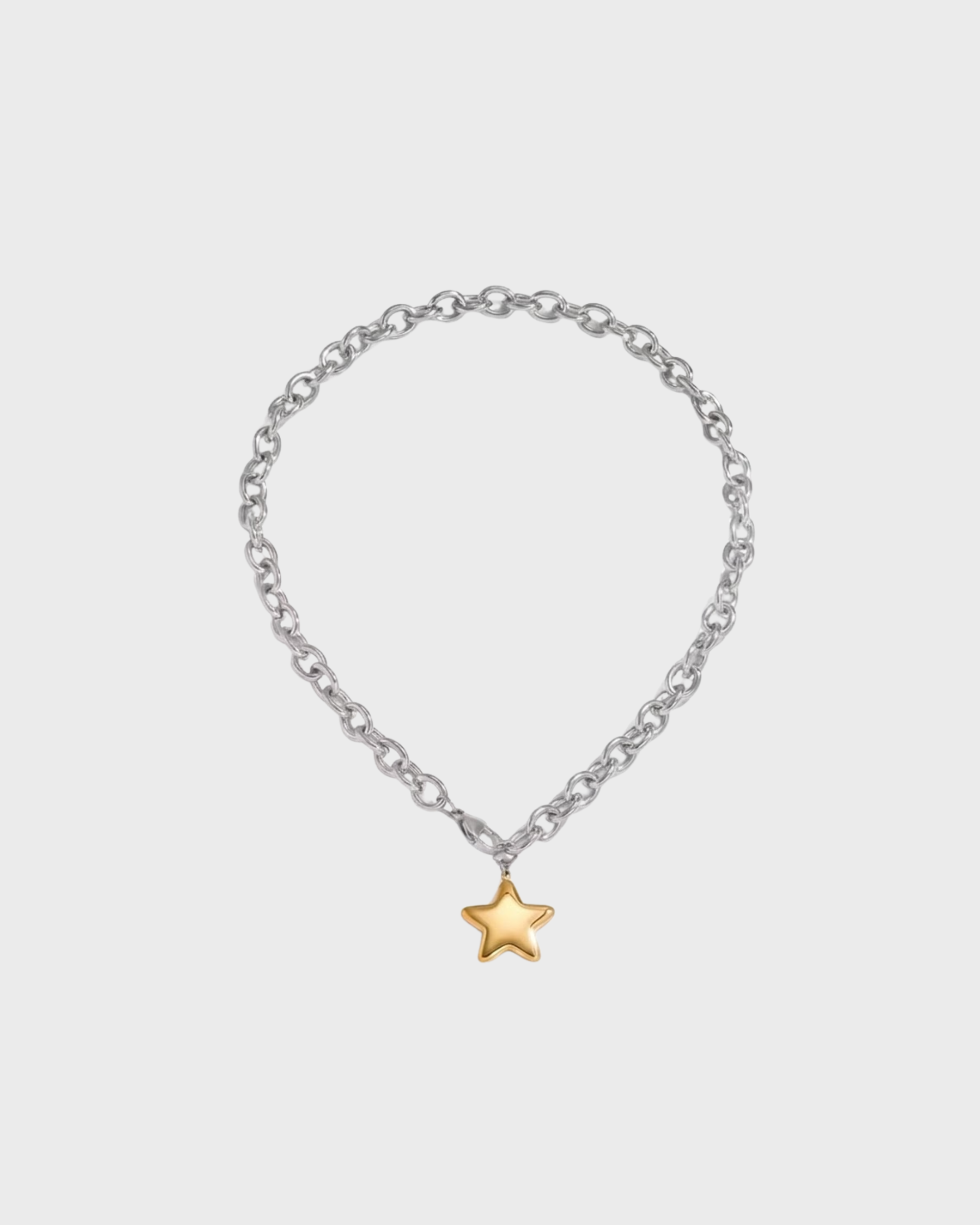 Silver chain bracelet with a gold star charm on a light gray background