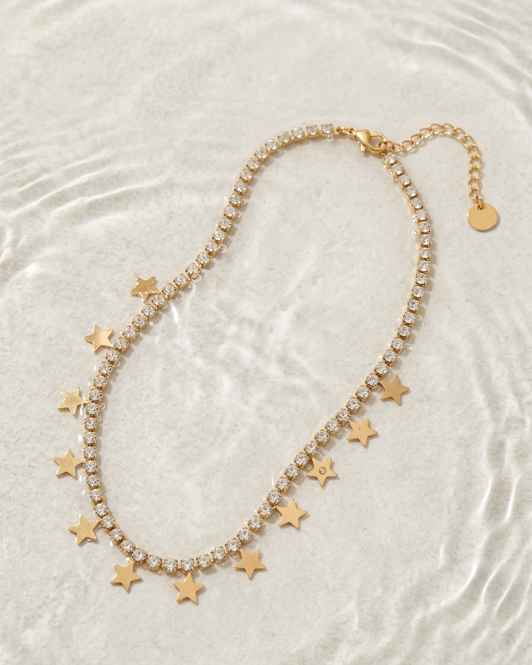 Gold necklace with star pendants on a textured white surface