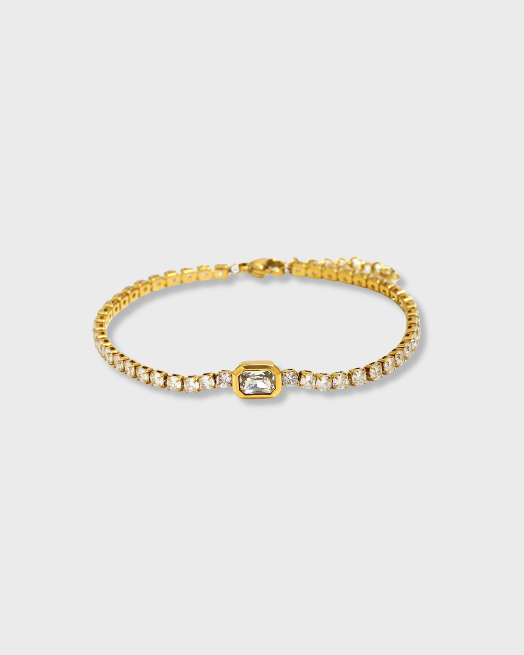 Gold bracelet with a central gemstone on a light gray background