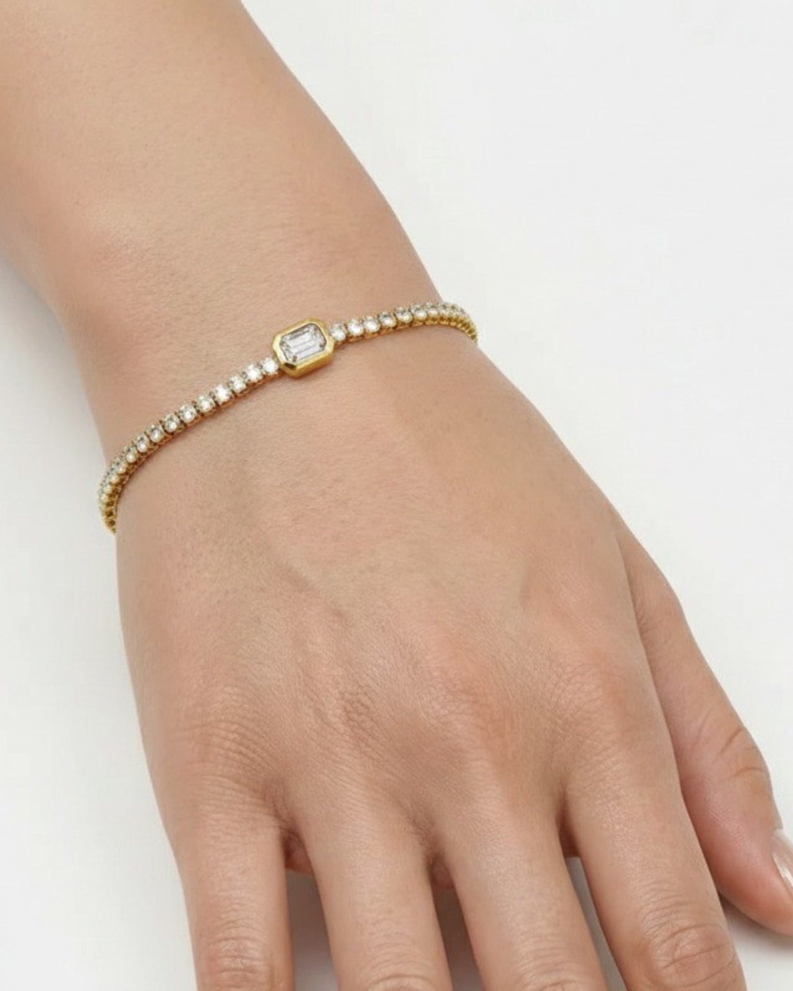 Gold bracelet with a diamond on a hand against a white background