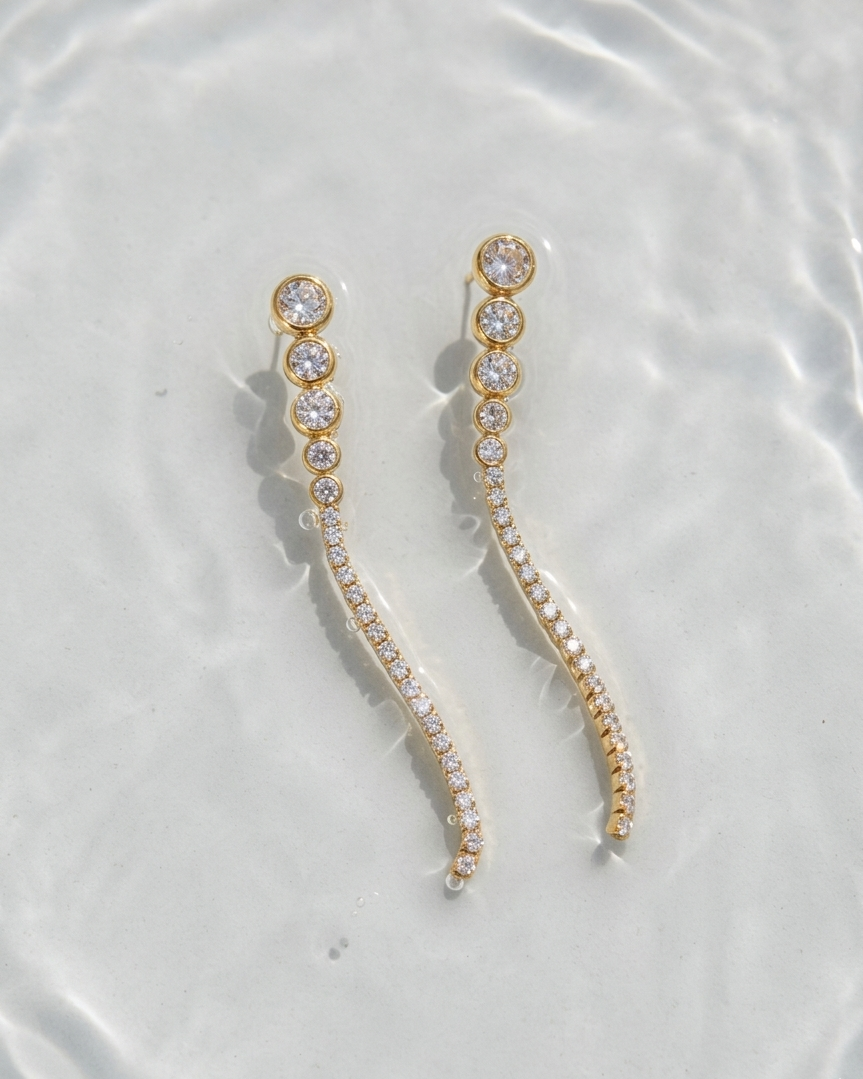 Gold and crystal earrings on a water surface