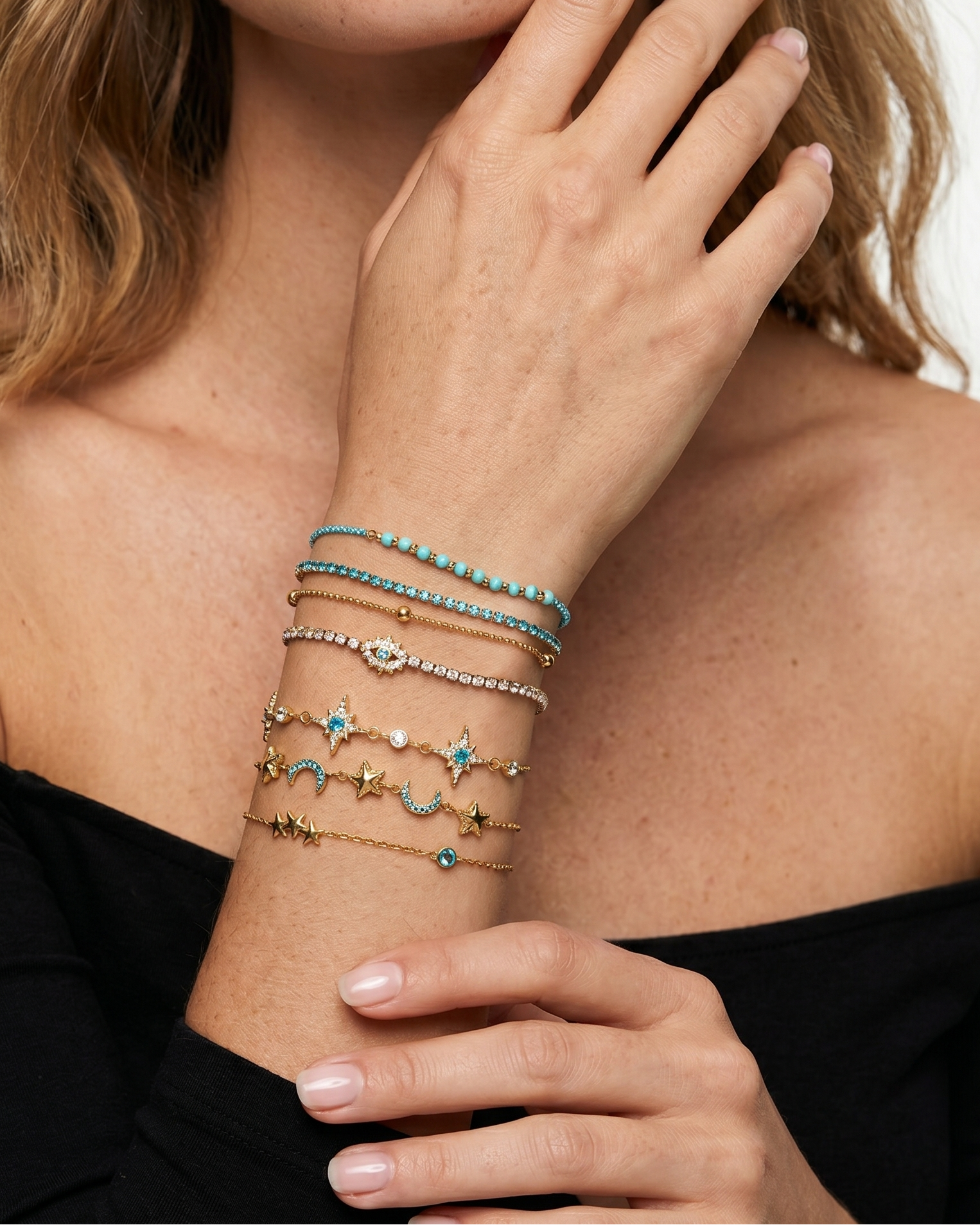 Woman wearing multiple bracelets on her wrist with a neutral background