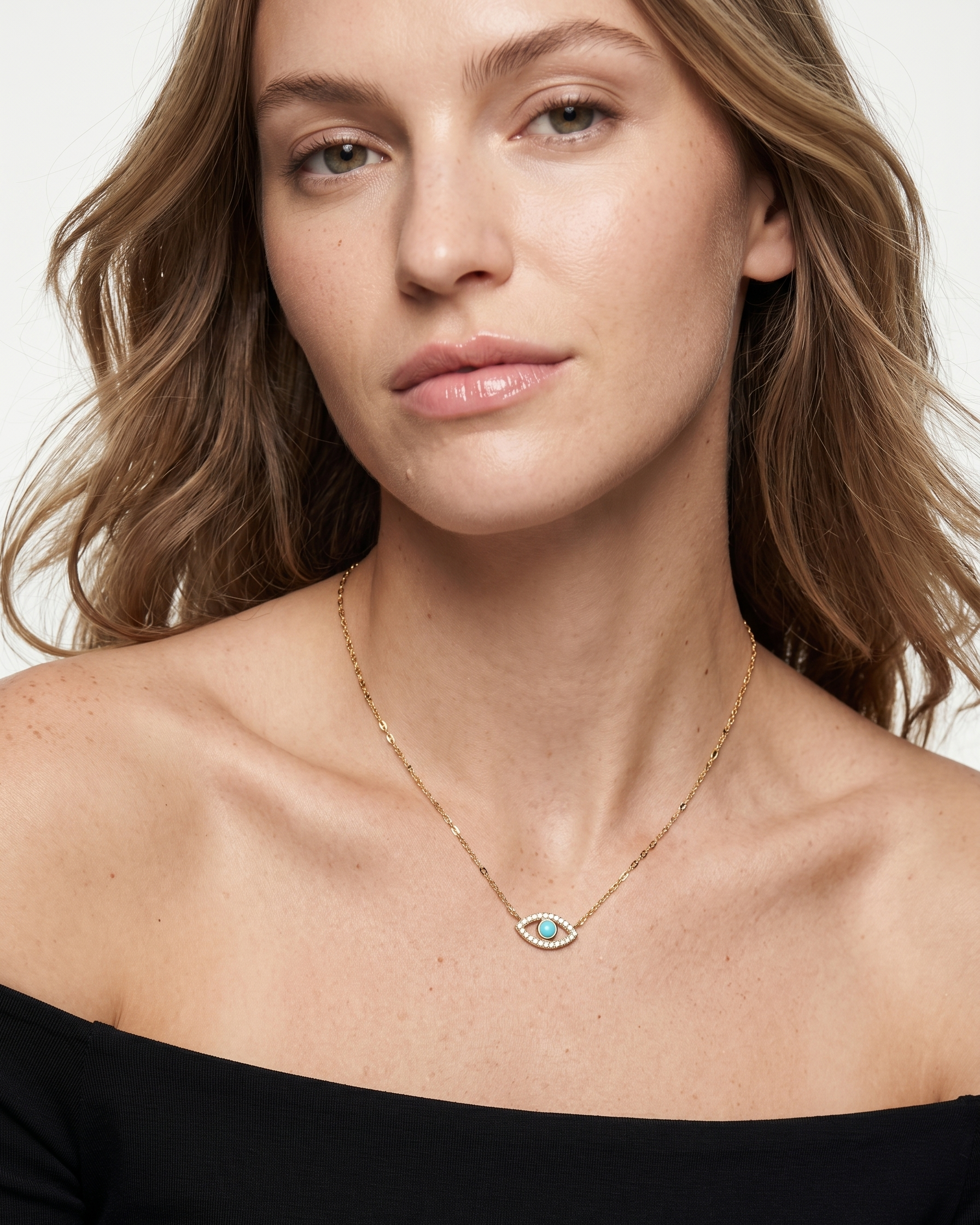 Woman wearing a gold necklace with a blue gemstone on a plain background