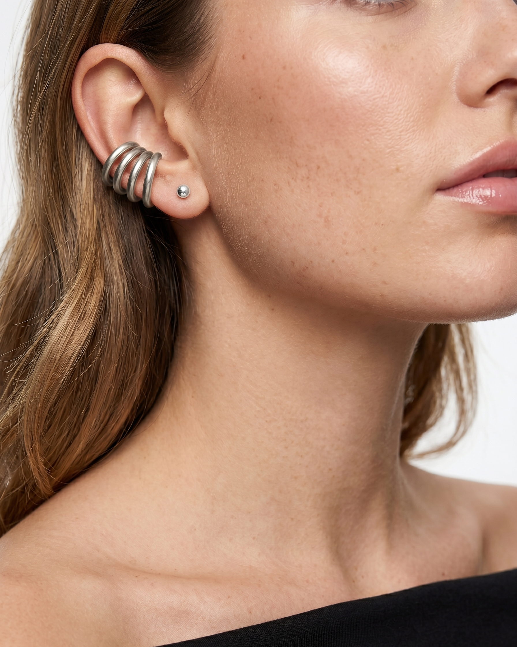 Close-up of a woman wearing a silver earring with a black background