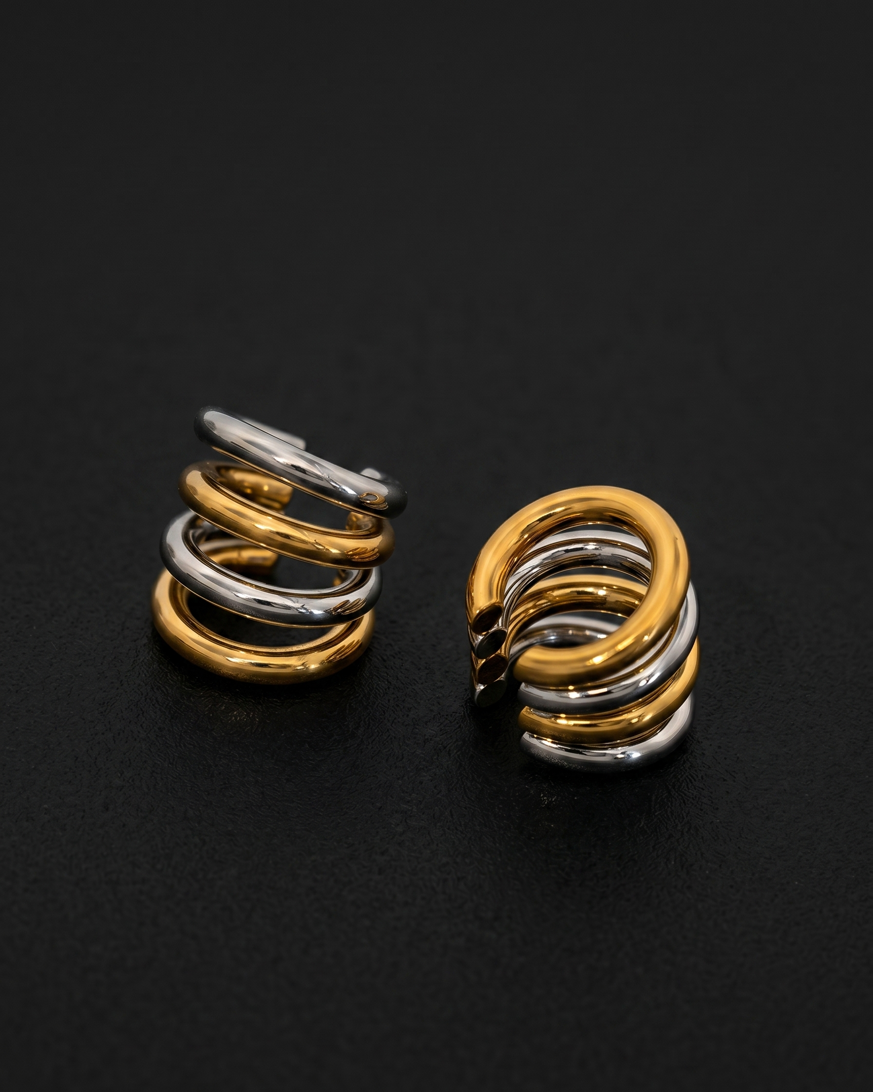 Pair of spiral earrings in gold and silver on a black background