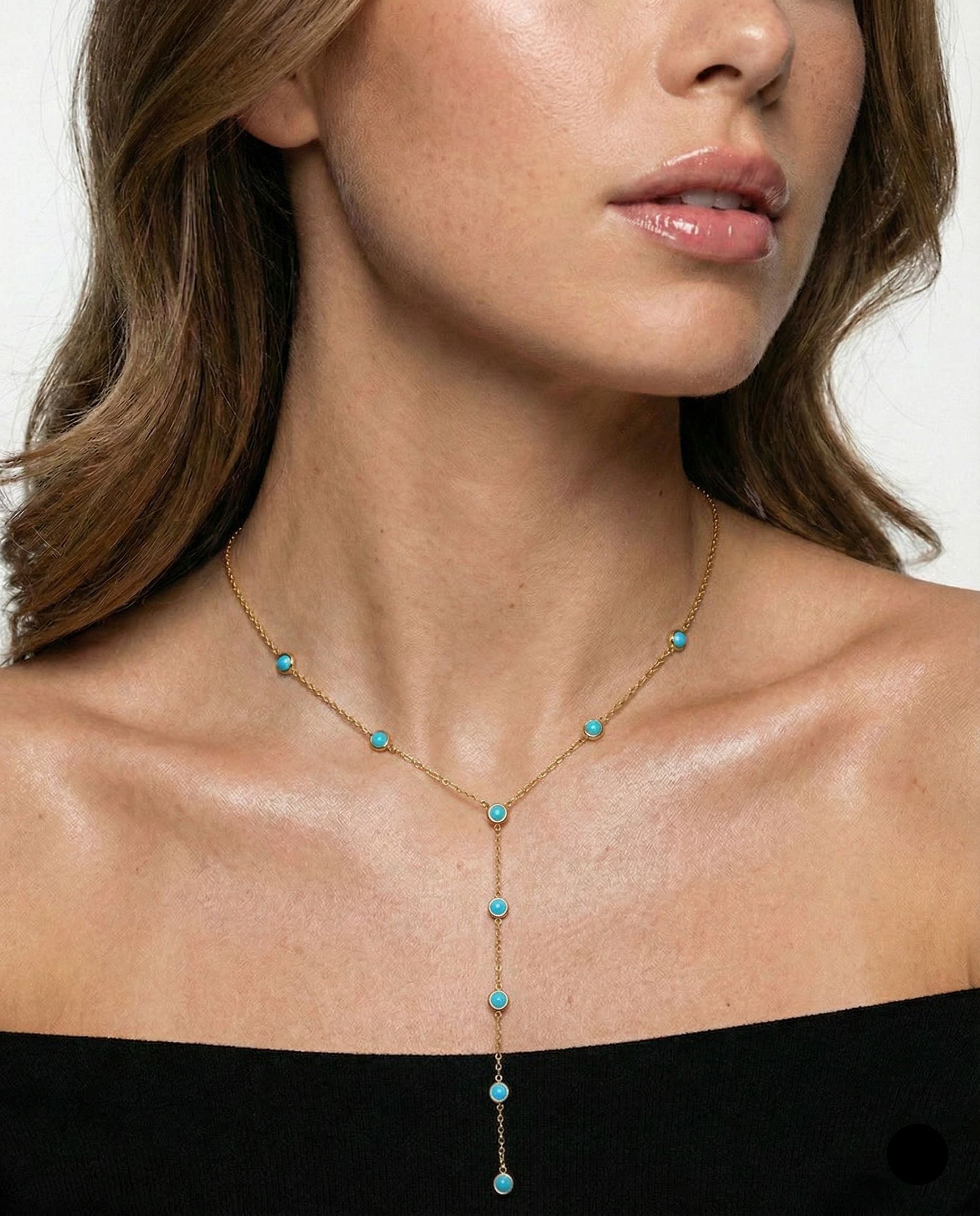 Necklace with turquoise beads worn by a model on a plain background