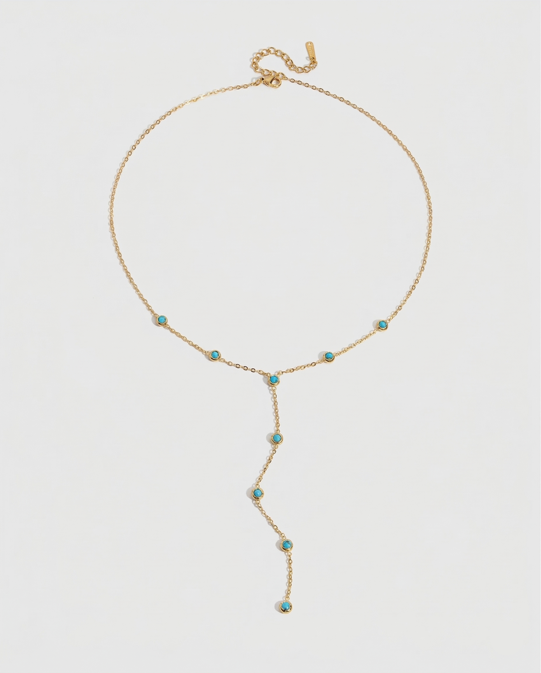 Gold necklace with turquoise stones on a light gray background
