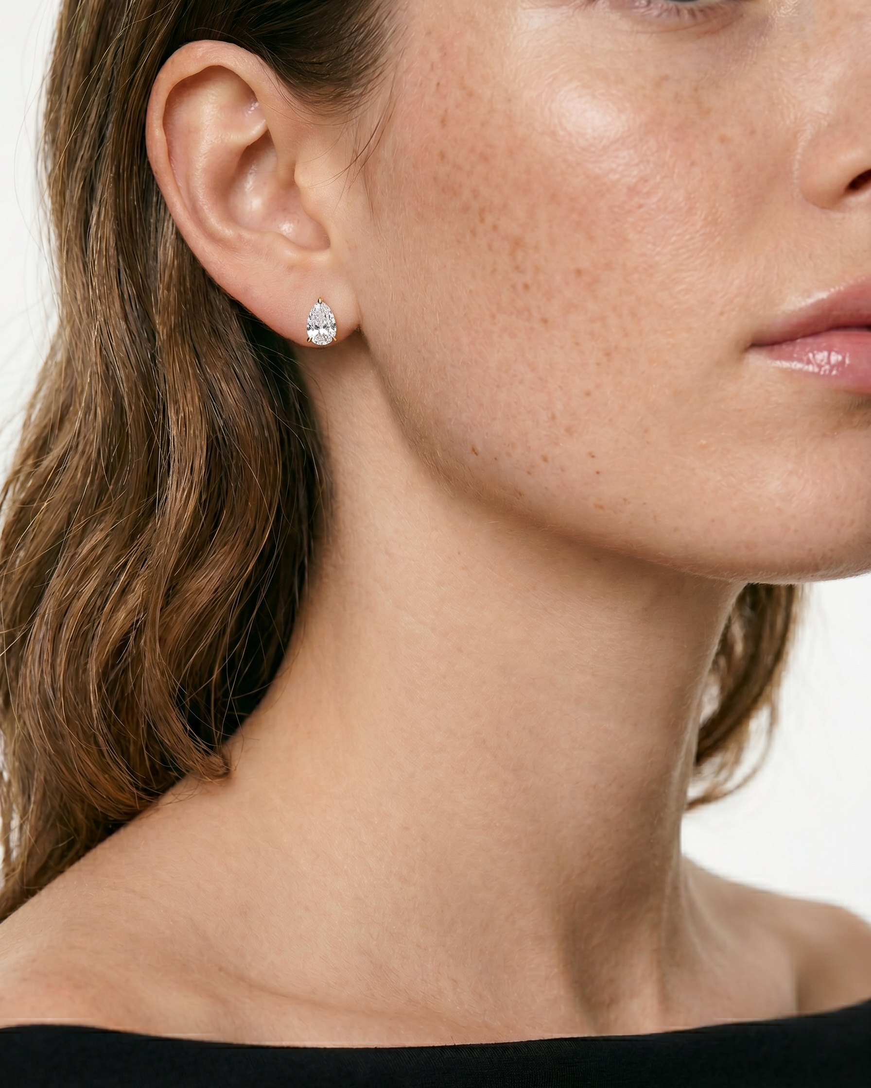 Close-up of a woman wearing a diamond earring on a plain background
