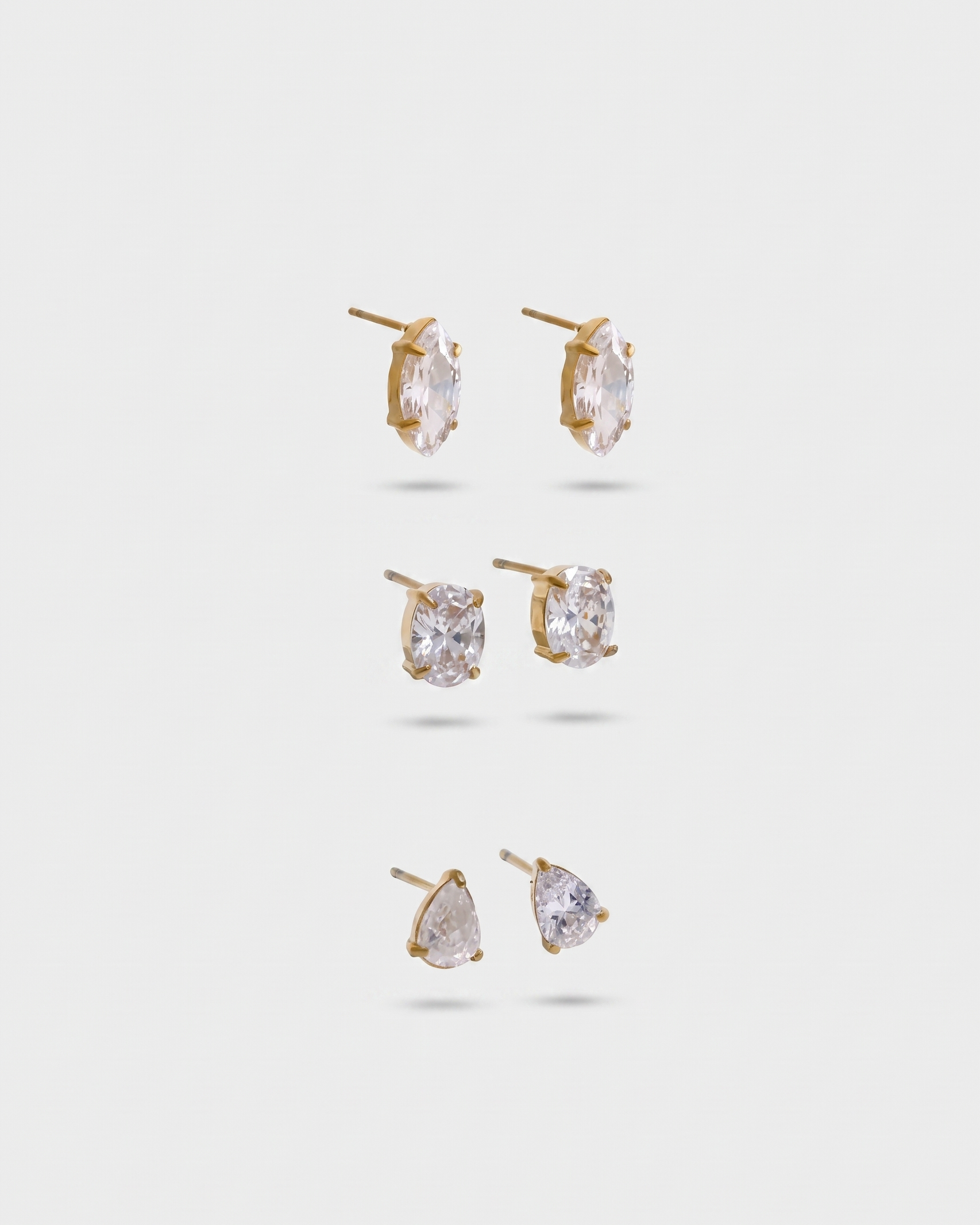 Set of gold earrings with clear gemstones on a white background