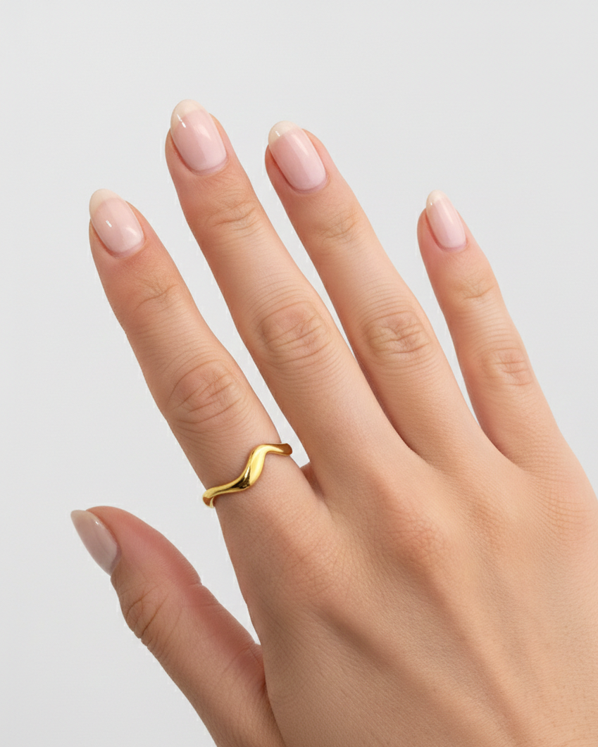 Hand wearing a gold ring with a plain background
