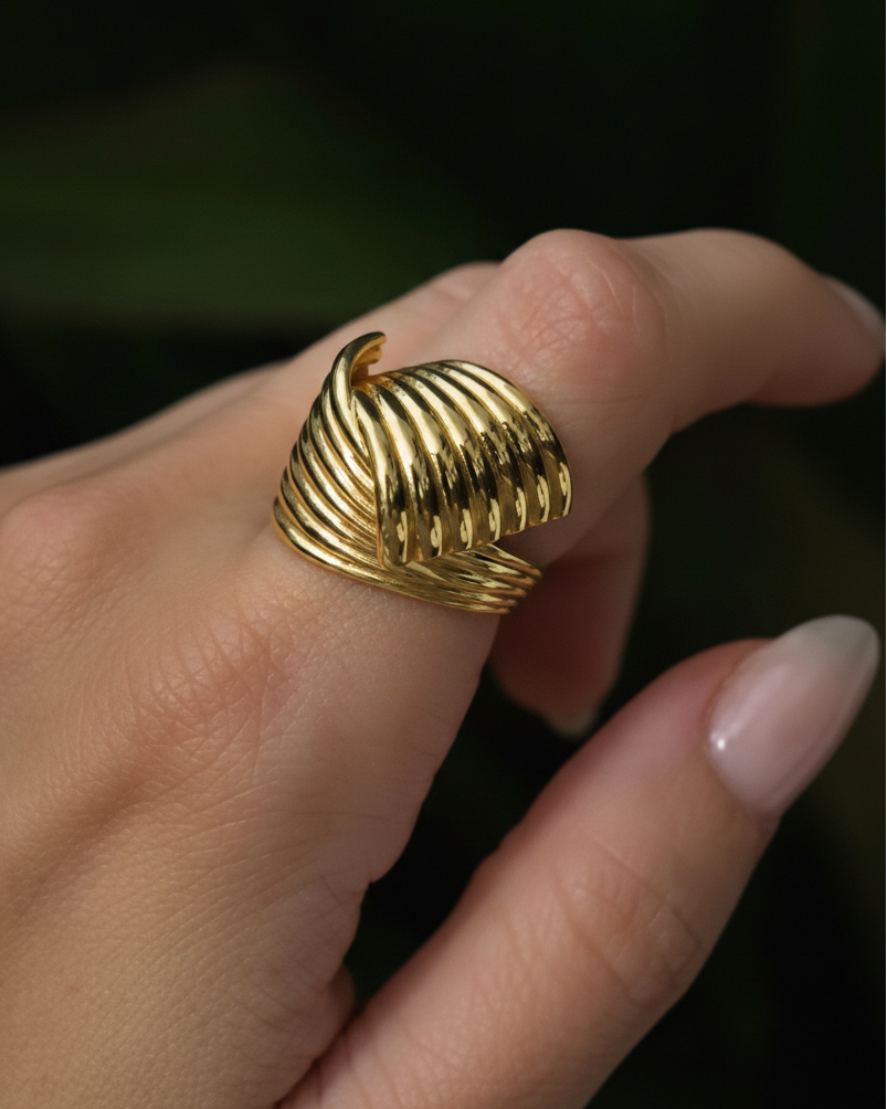 Gold ring on a finger against a dark background
