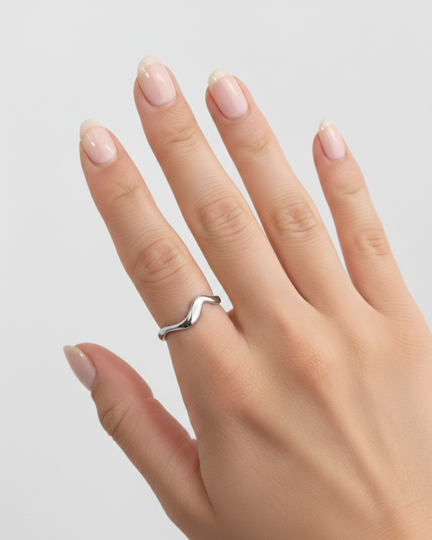 Hand wearing a silver ring on a light gray background