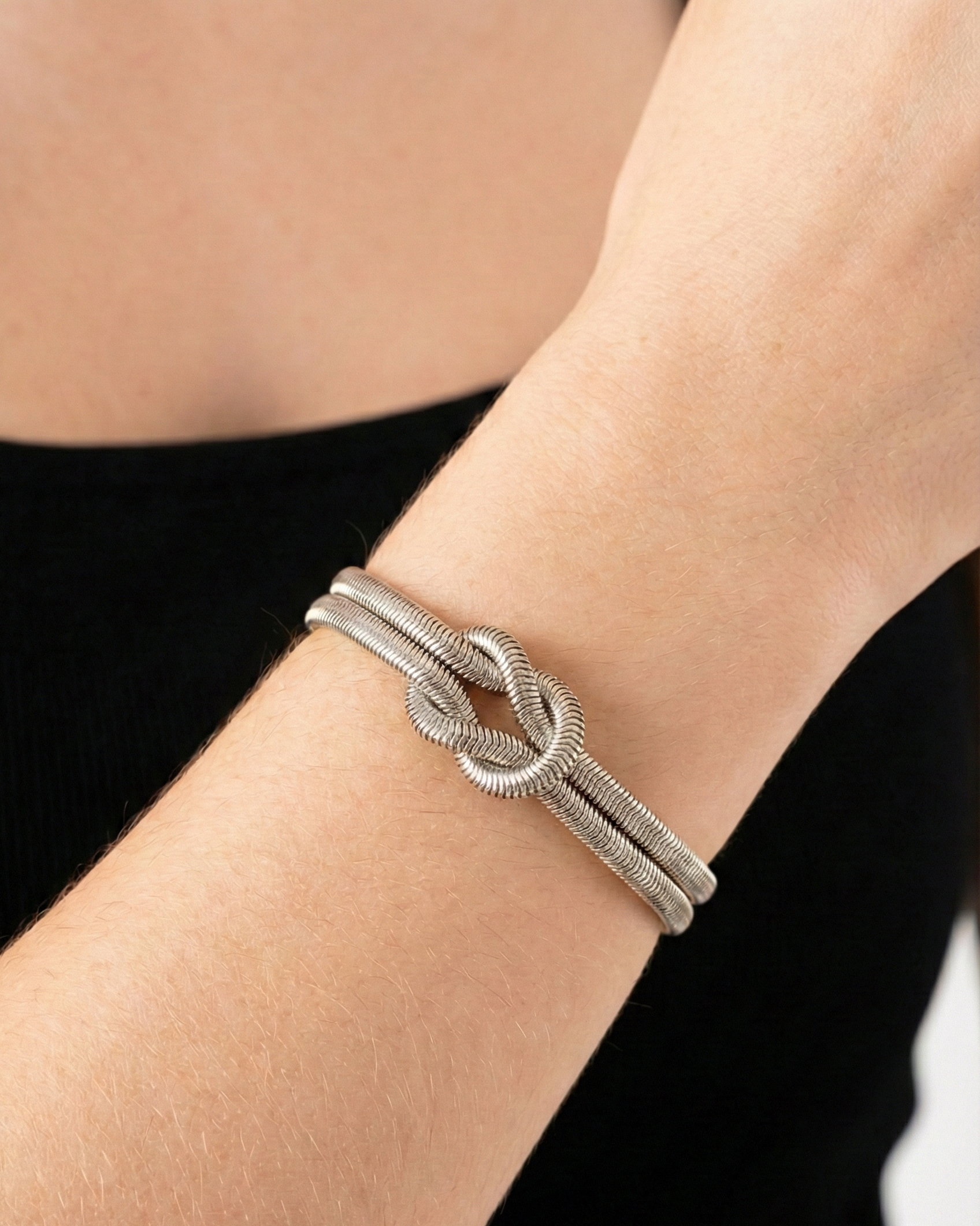 Silver knot bracelet on a wrist with a blurred background