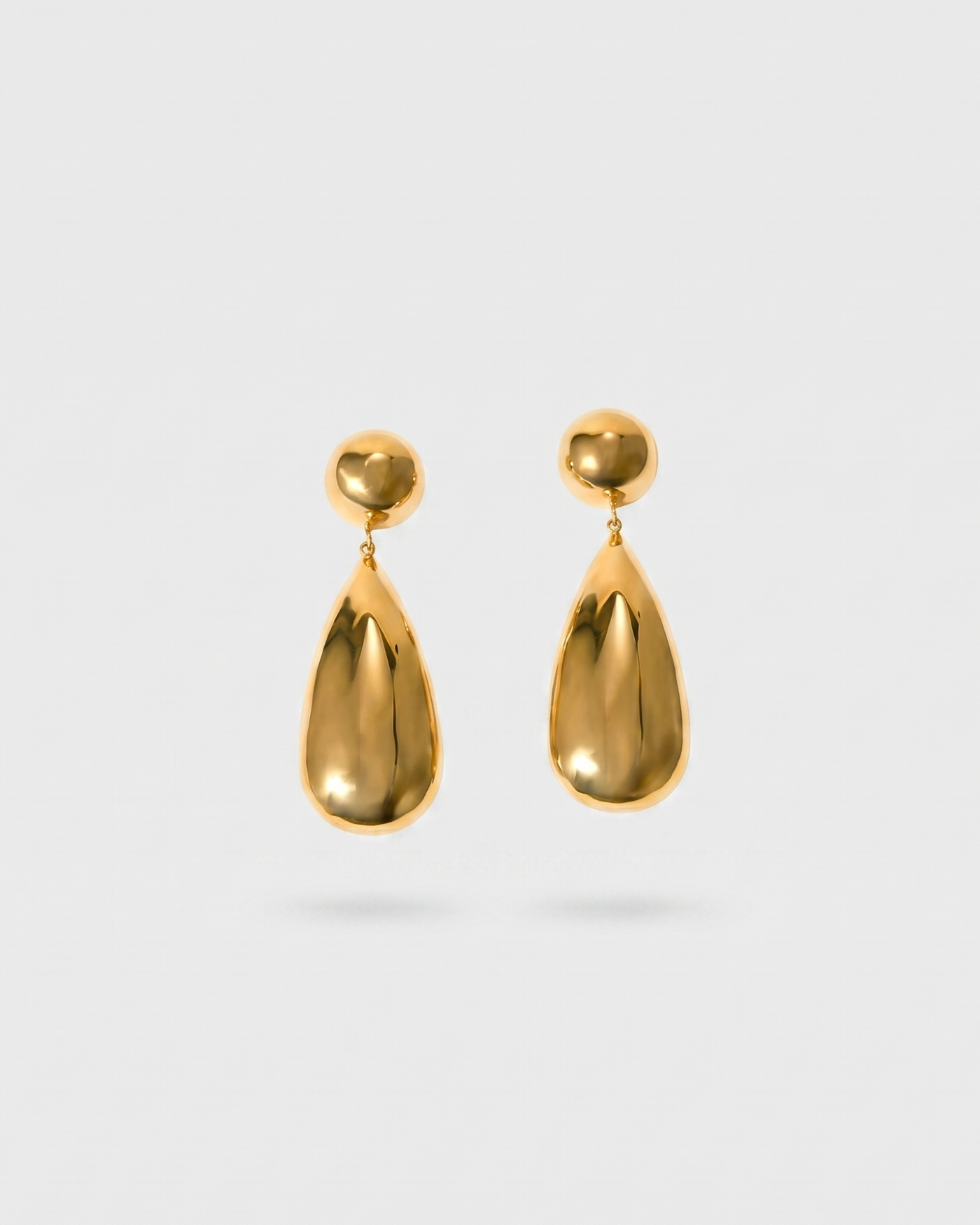 Gold teardrop earrings on a light gray background