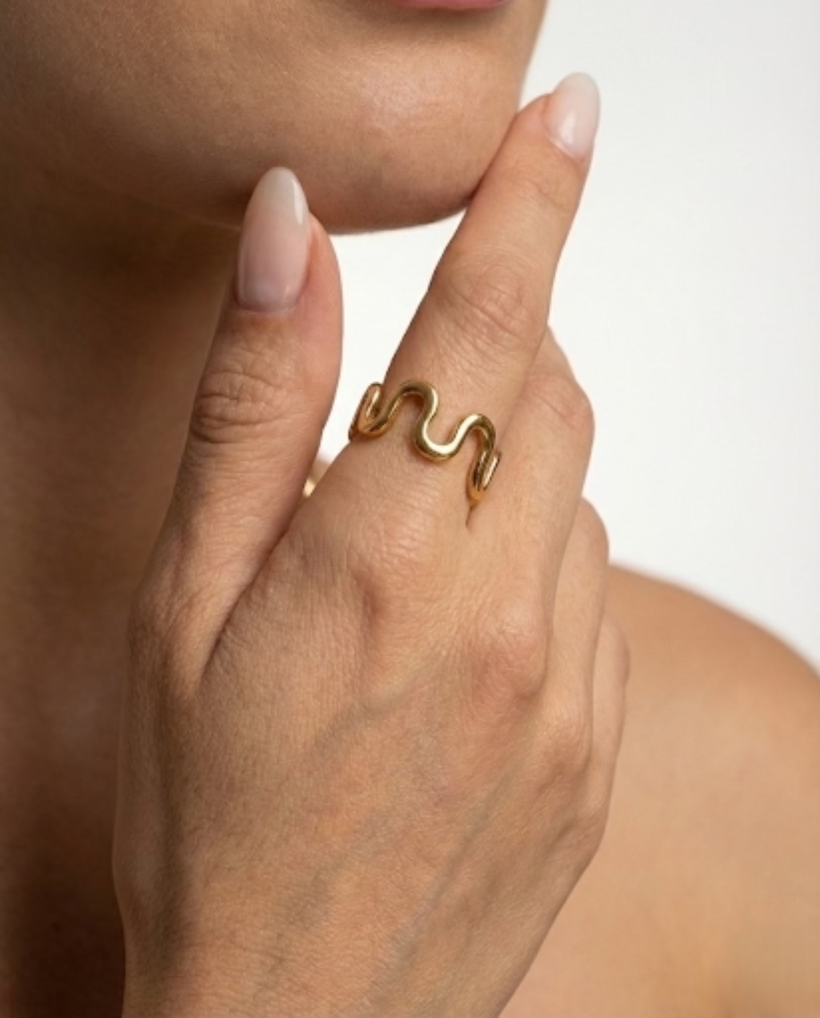 Gold ring on a finger with a neutral background