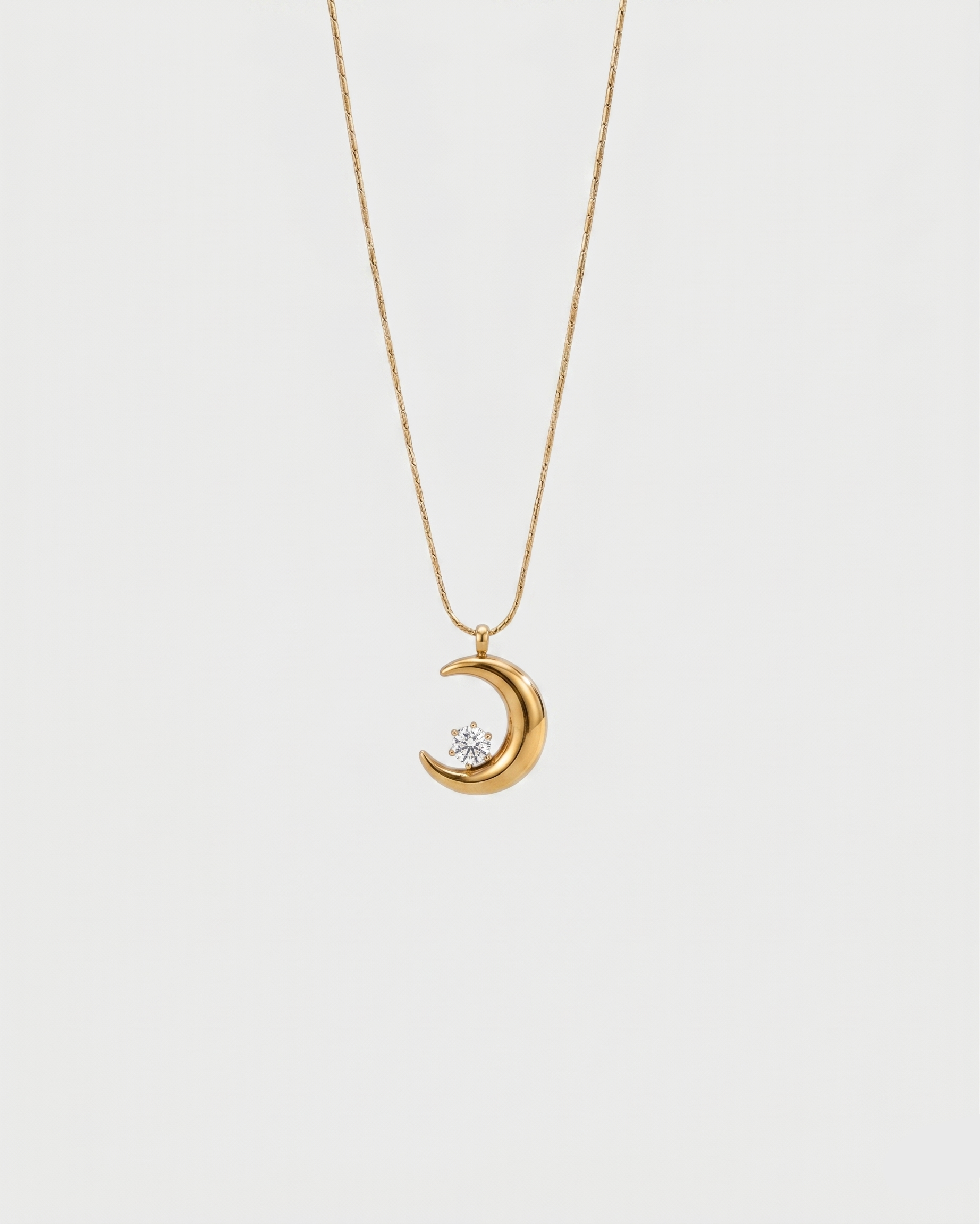 Gold necklace with a crescent moon pendant on a white background
